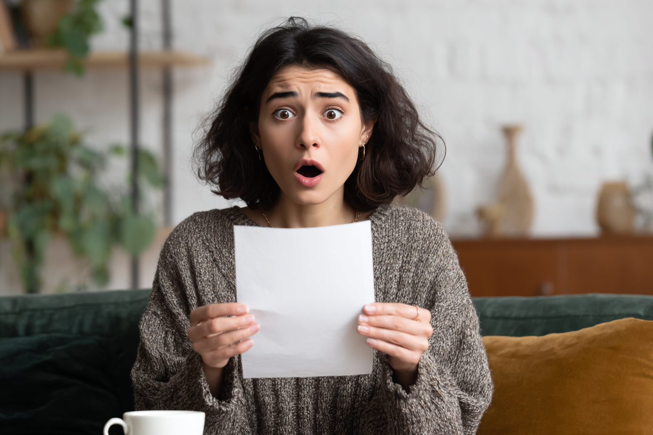 A shocked woman holding a piece of paper | Source: Midjourney