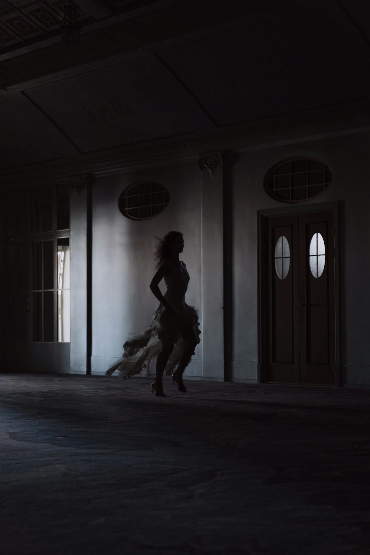 Silhouette of a woman running on a dimly lit hallway | Source: Pexels