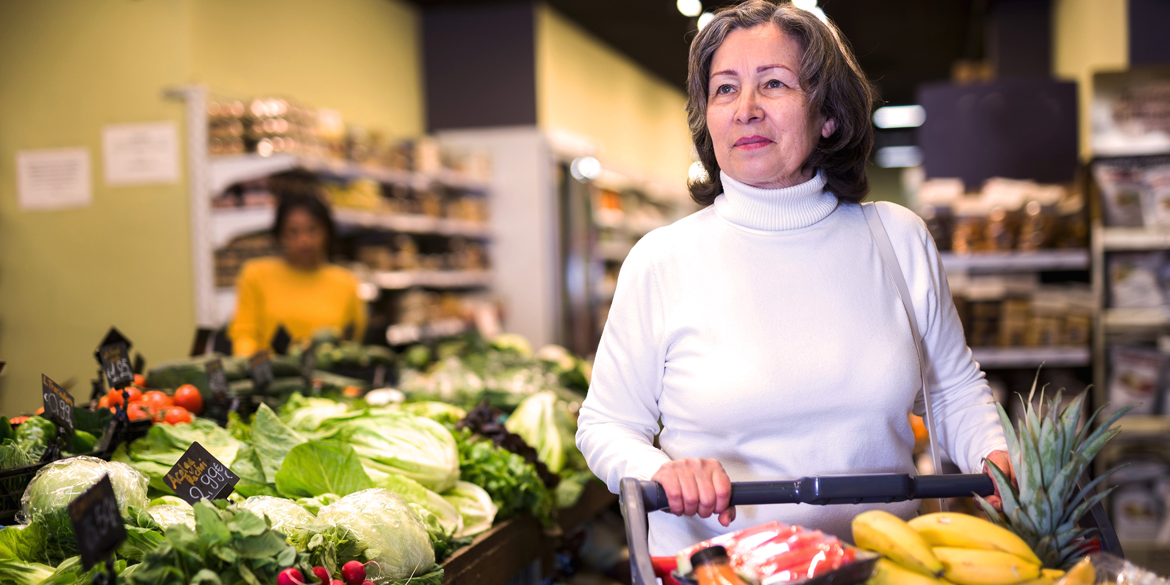 A senior woman grocery shopping in the produce section | Source: Shutterstock