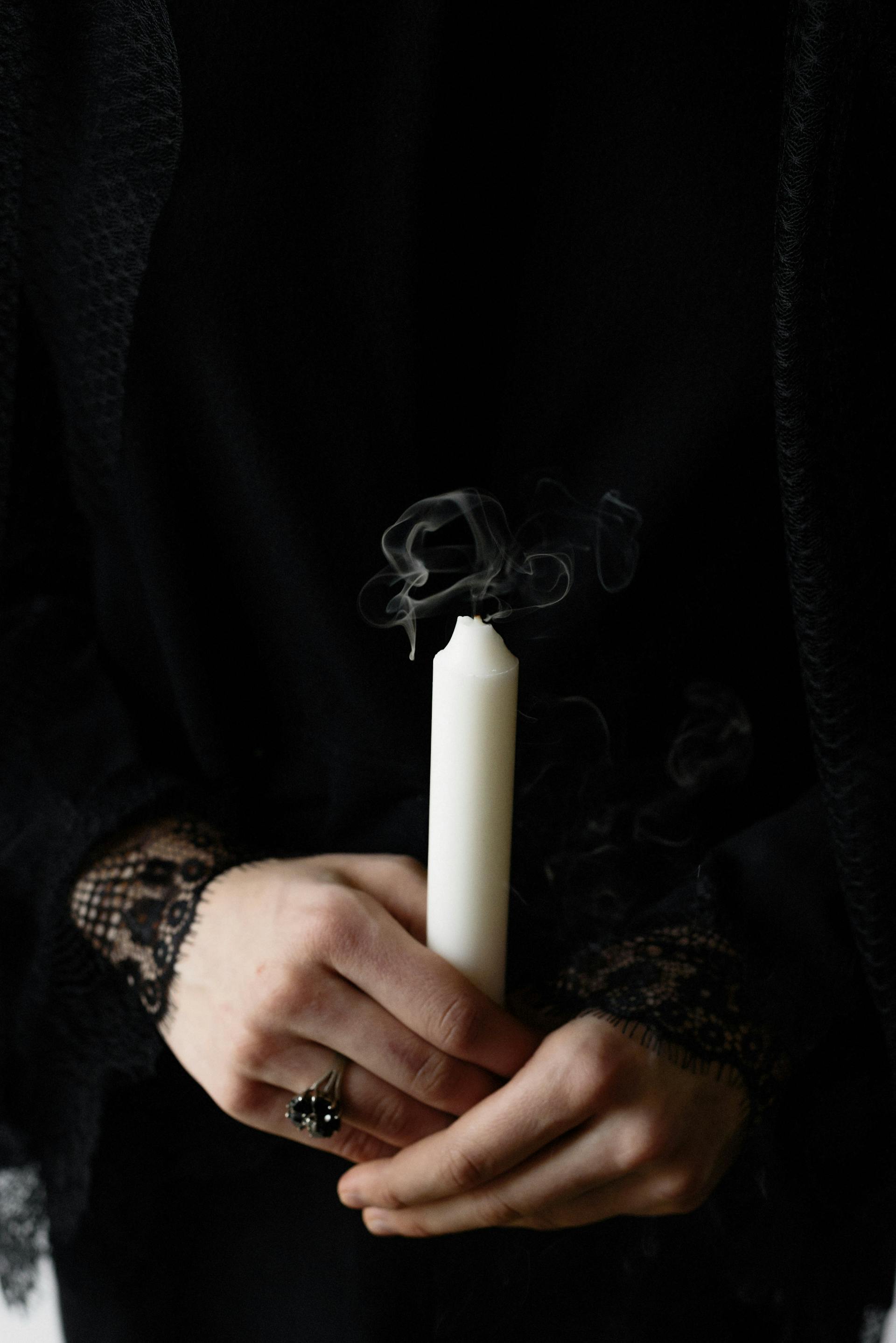 Close-up of a woman holding a white candle | Source: Pexels
