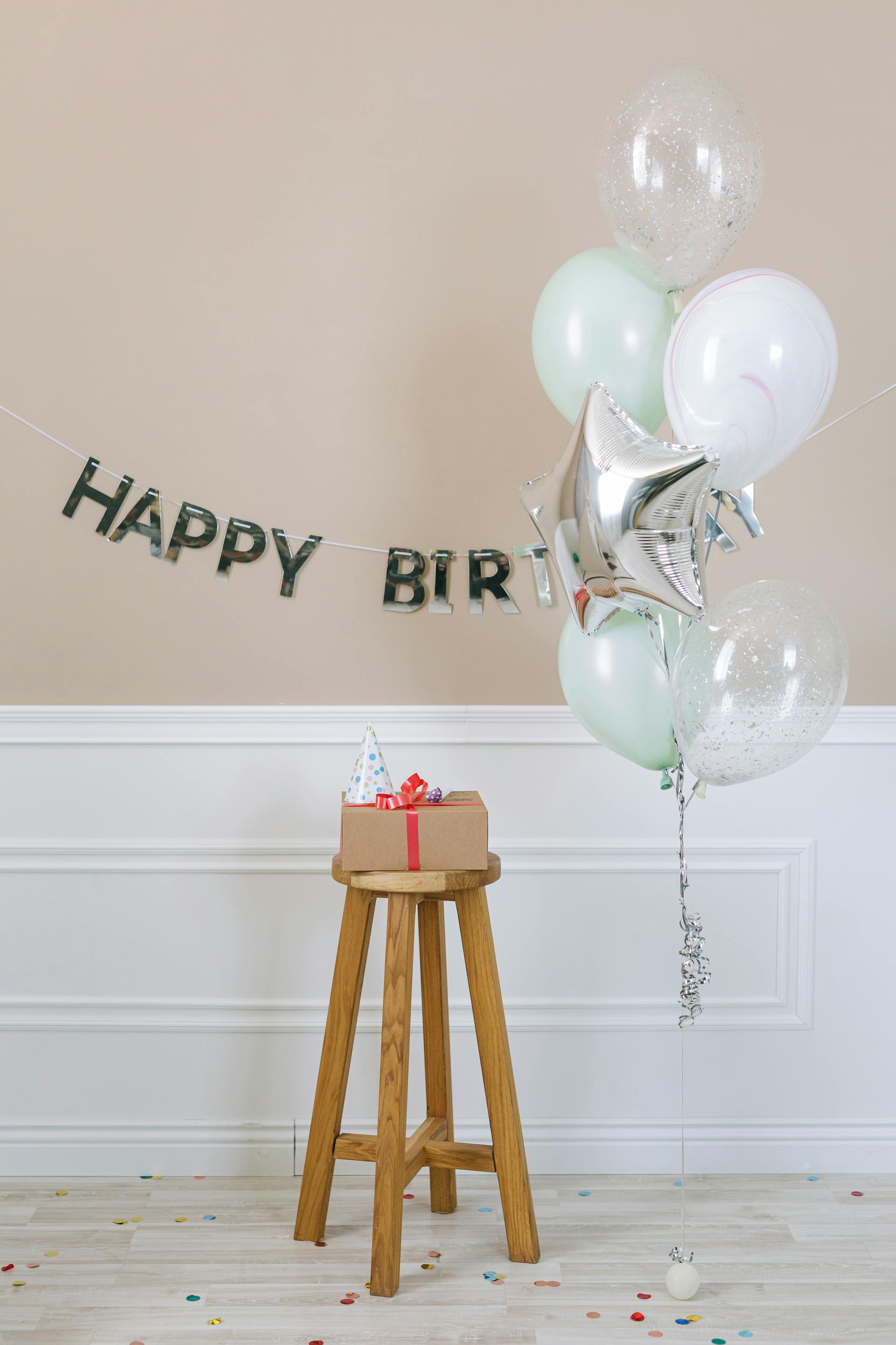 A birthday present lying on a wooden stool placed next to balloons | Source: Pexels