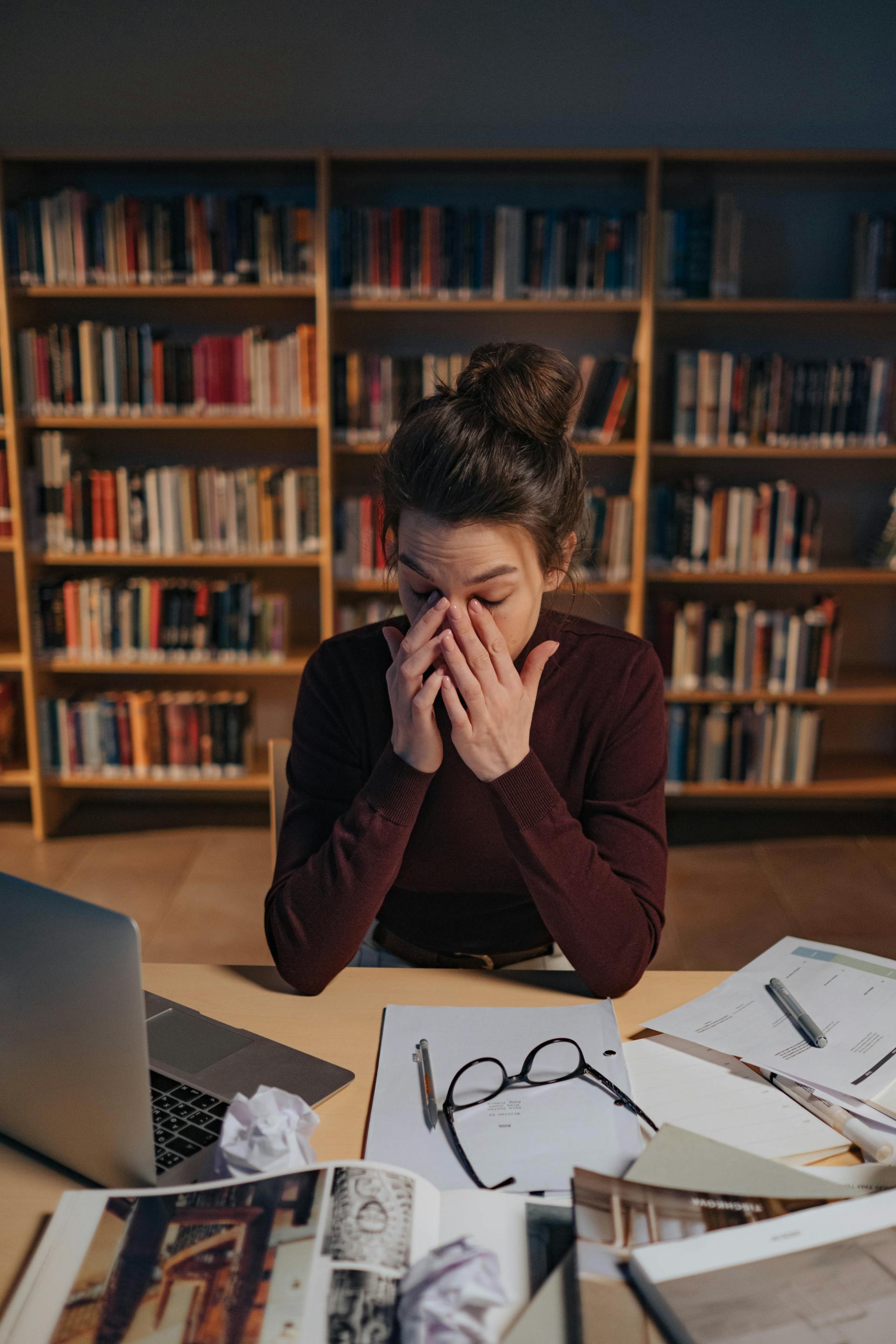 A tired woman working in a library | Source: Pexels