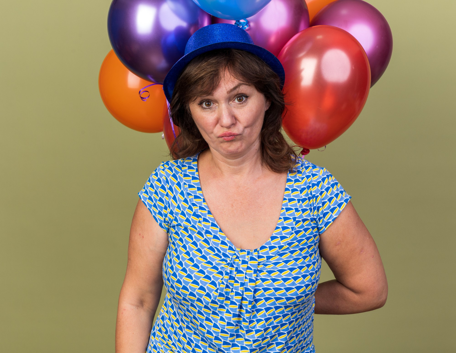 A stunned woman holding colorful balloons | Source: Freepik