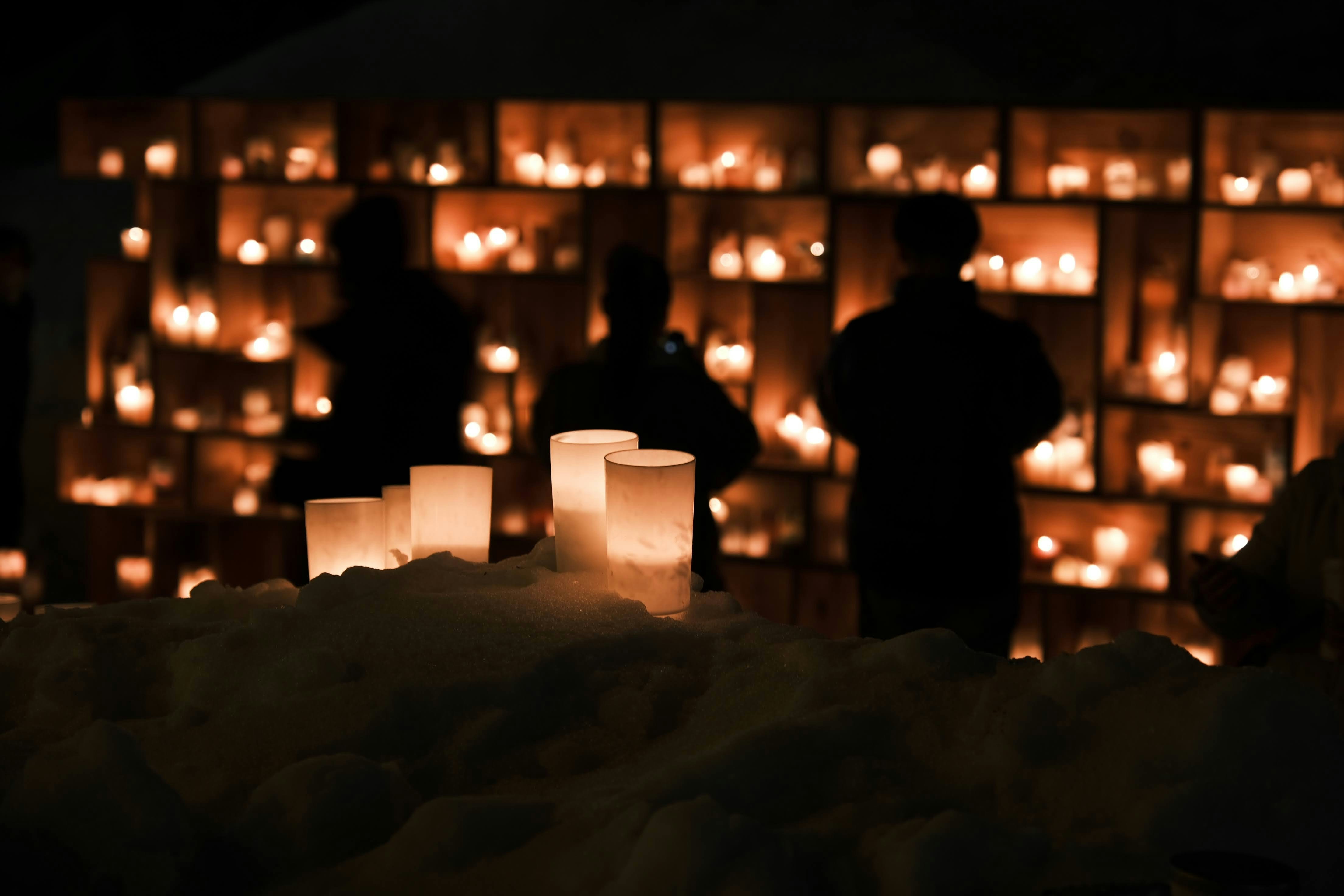 People standing in front of a wall of candles | Source: Pexels