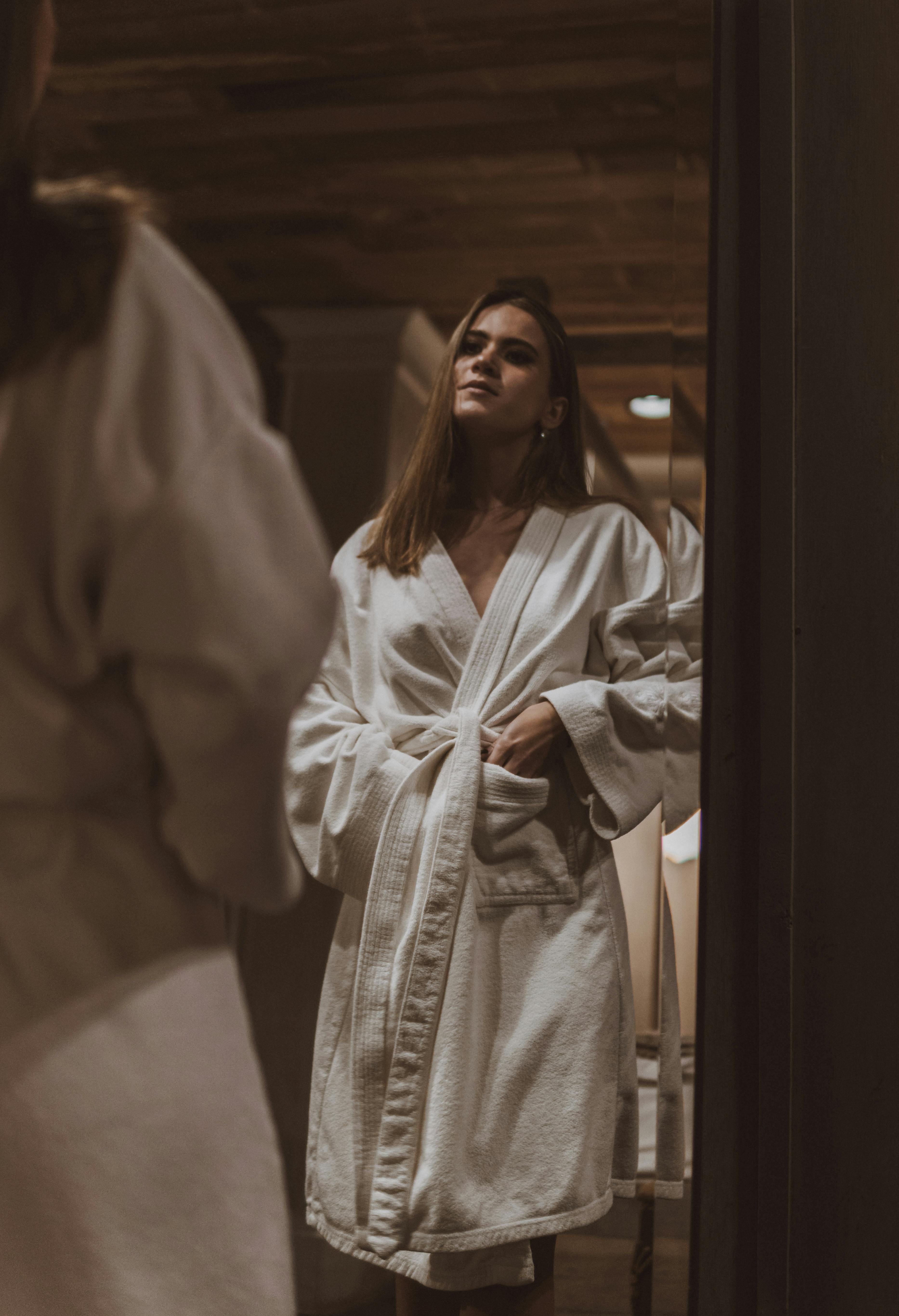 A woman in a bathrobe looking at the mirror | Source: Pexels