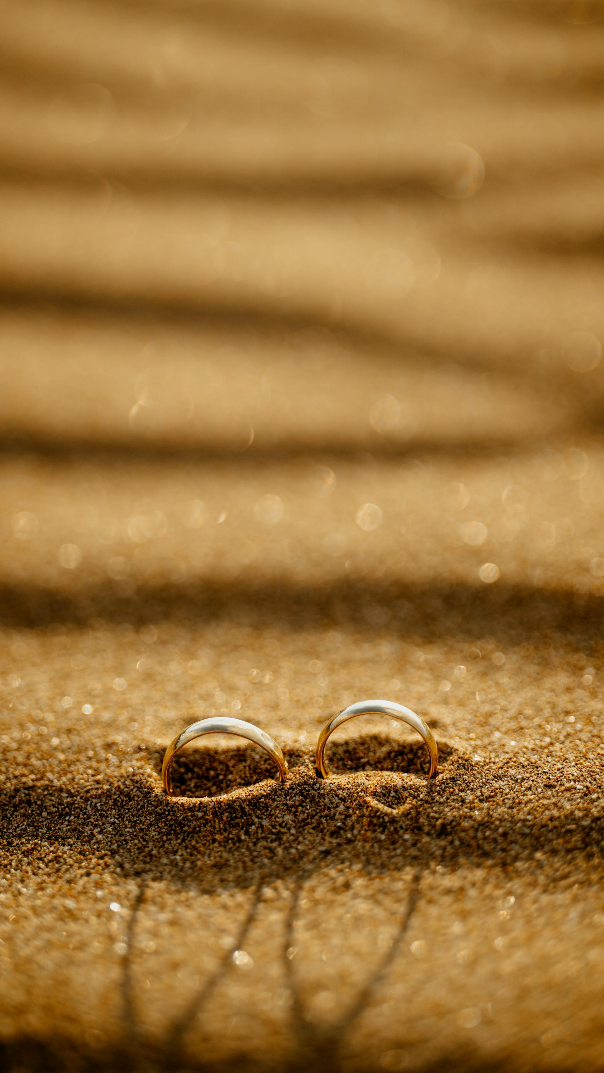 Wedding rings on a sandy beach at sunset | Source: Pexels