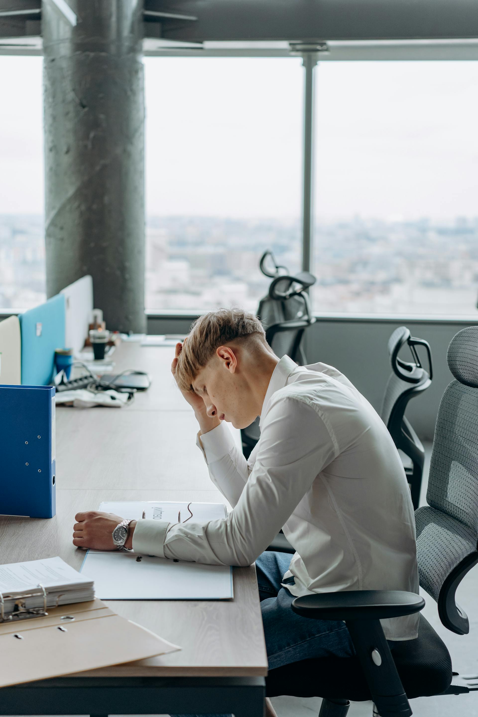 A man sitting in the office with a hand on his head | Source: Pexels