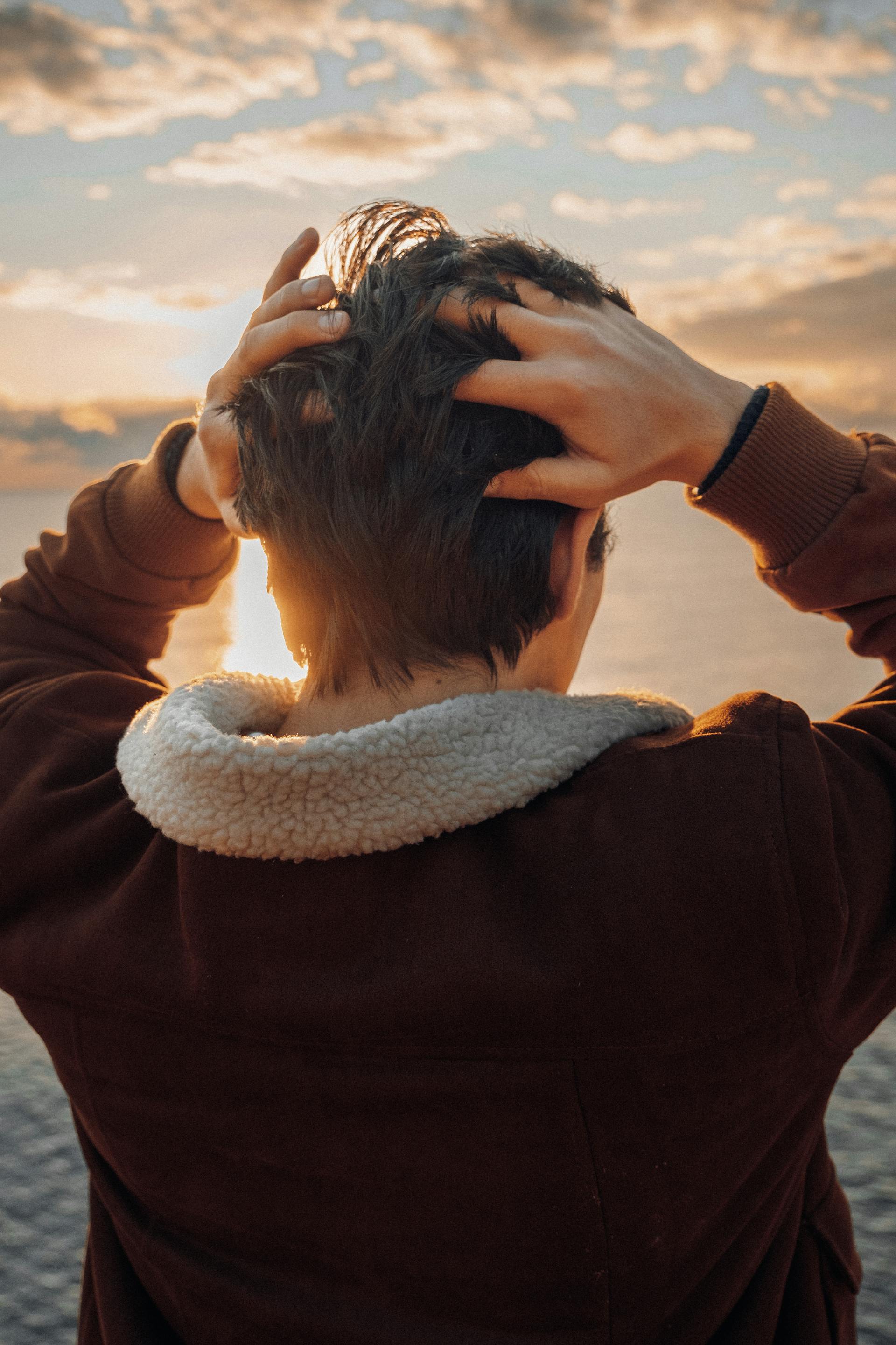 A youngster touching the back of his head while standing on the beach | Source: Pexels