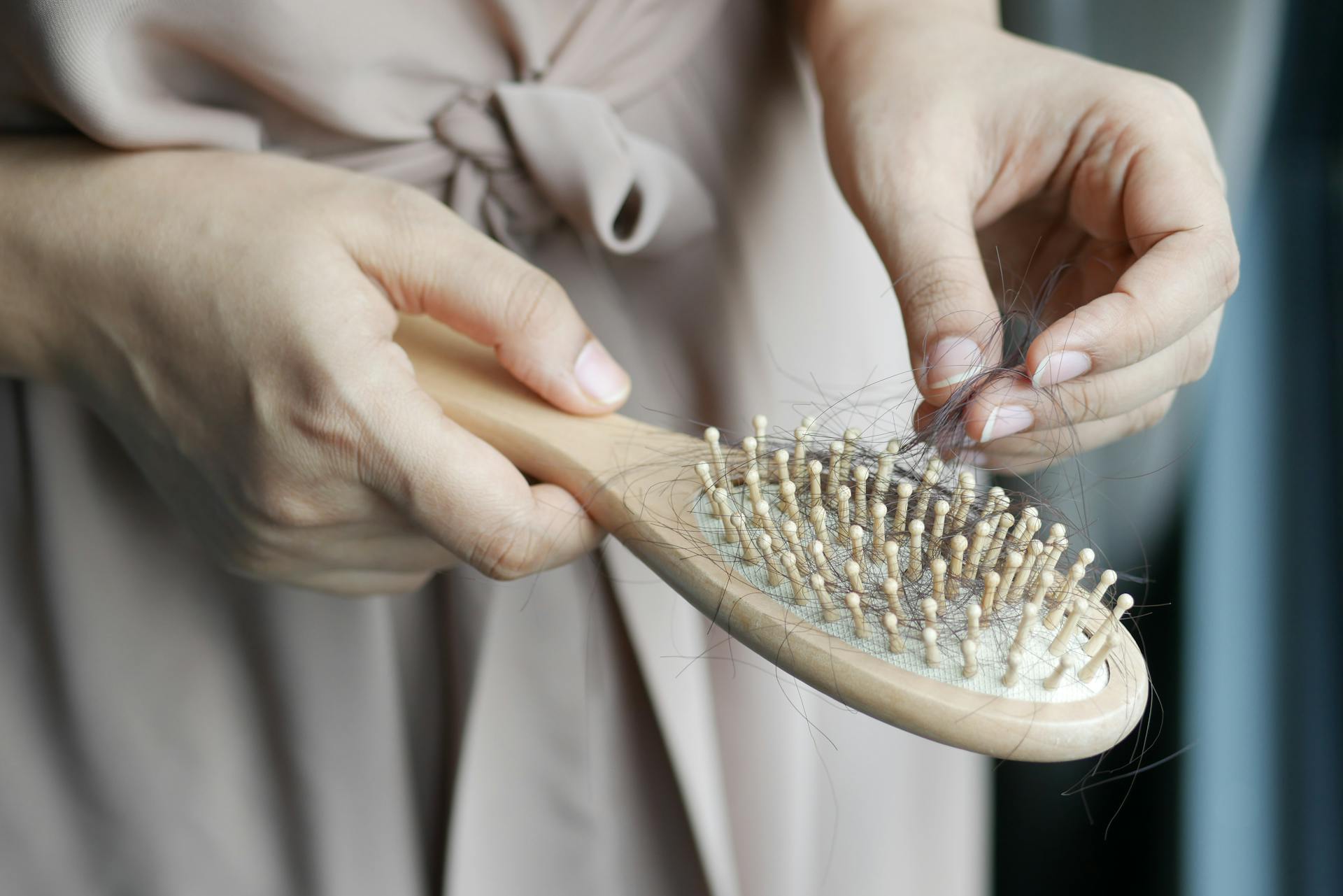 Cropped shot of a woman removing hair from a brush | Source: Pexels