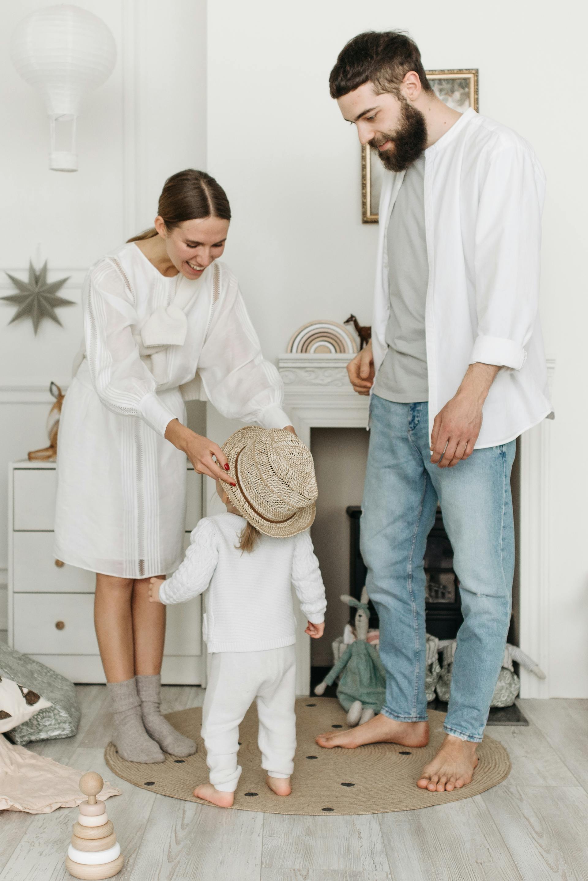 A man watching a woman put a hat on a young girl | Source: Pexels