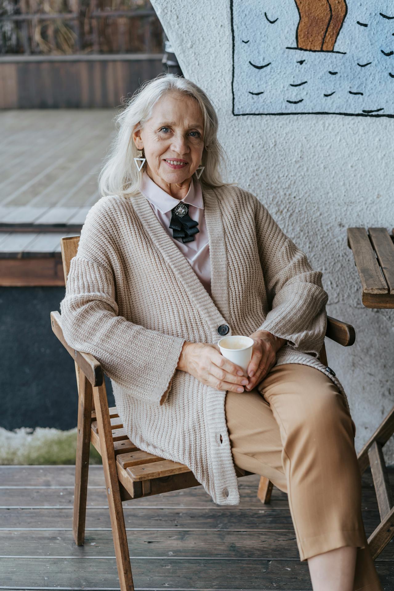 A cheerful older woman sitting on a chair | Source: Pexels