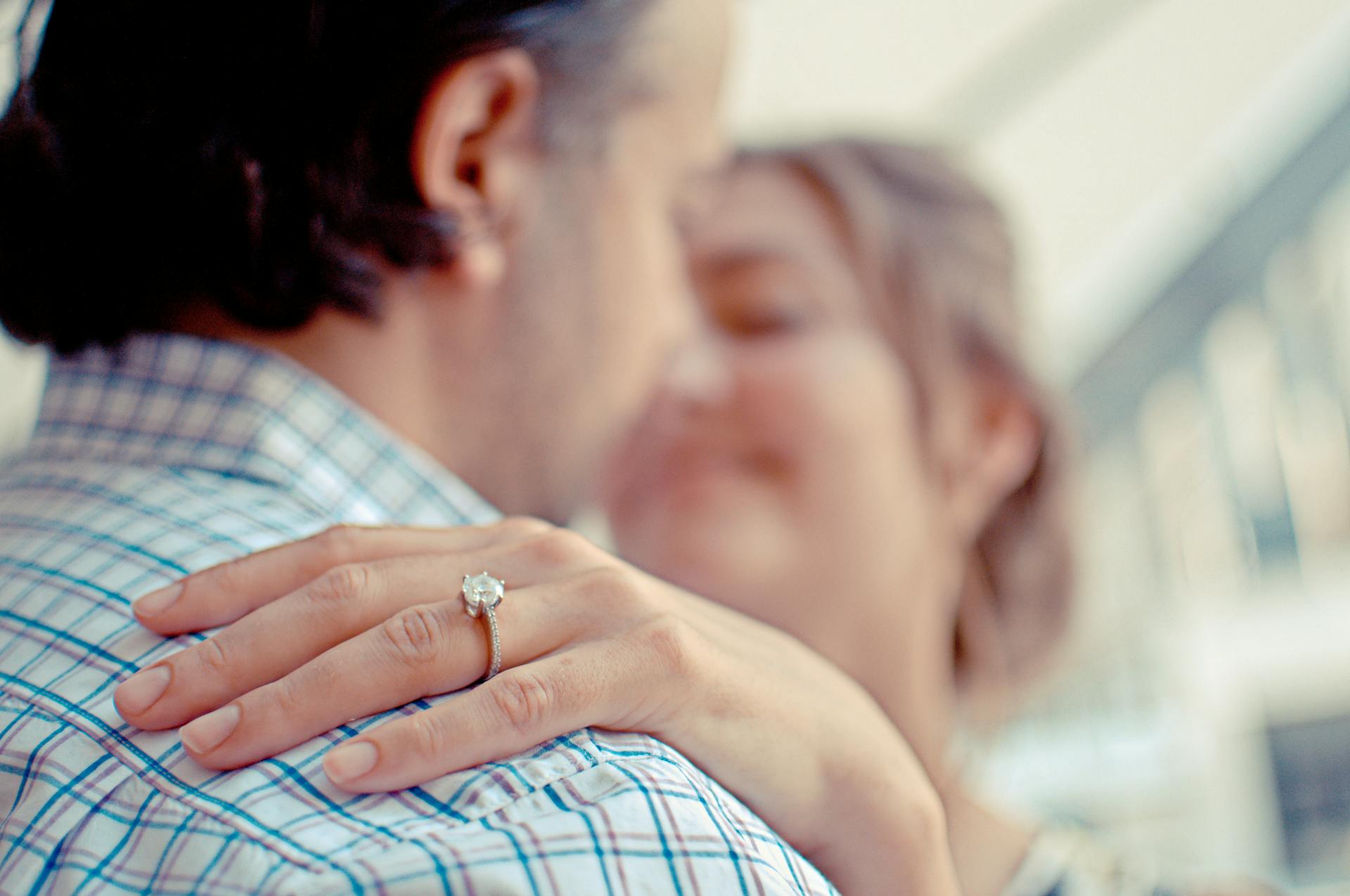 A couple hugging and showing off an engagement ring on her hand | Source: Pexels