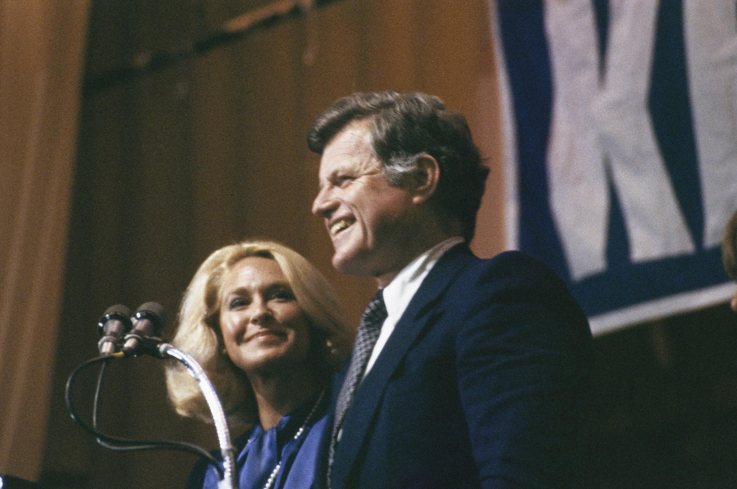 Joan Kennedy smiles as her husband, Senator Ted Kennedy, addresses a crowd of supporters after narrowly winning the Pennsylvania presidential primary election on April 22, 1980, in Philadelphia | Source: Getty Images