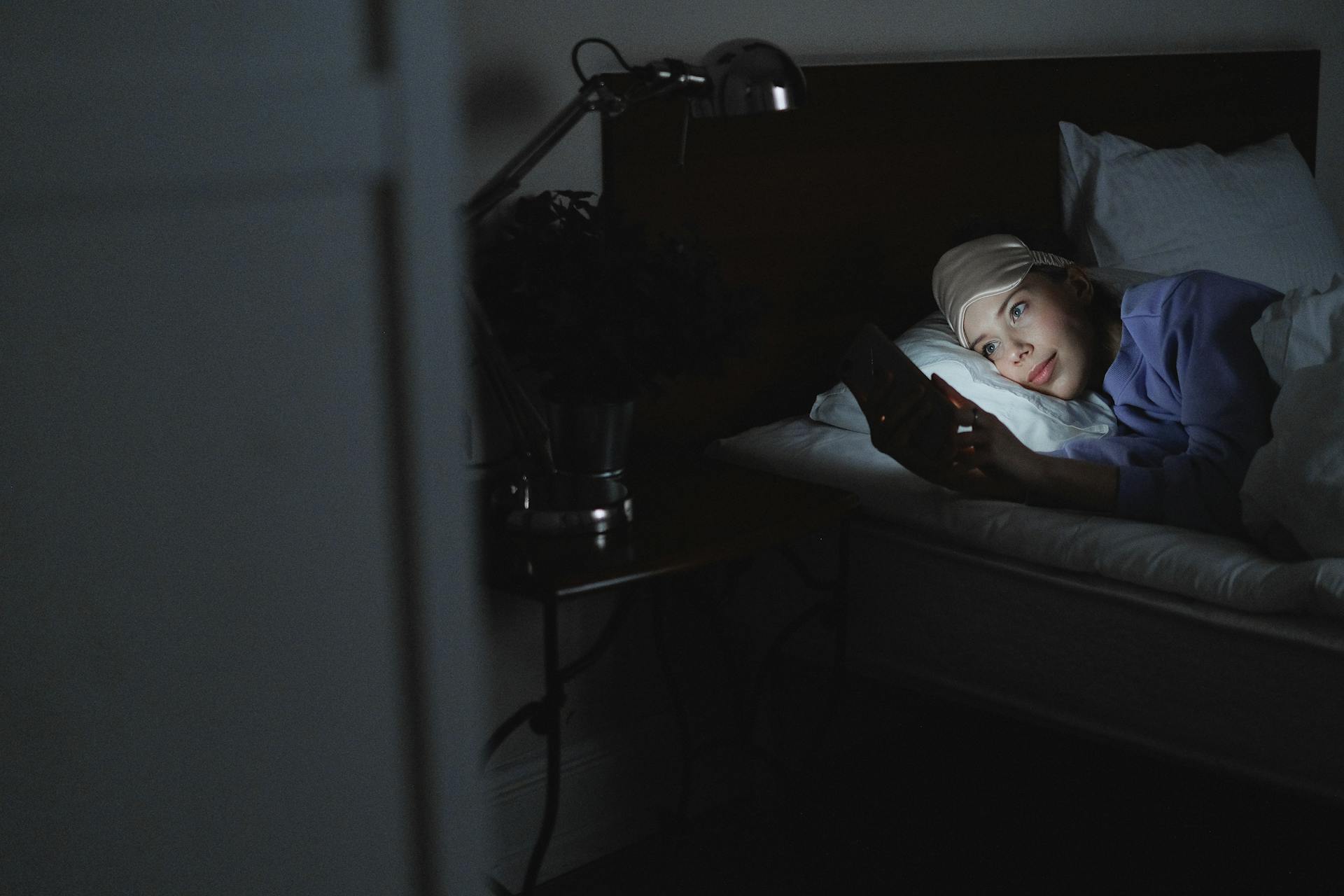 A woman in bed holding a cellphone | Source: Pexels