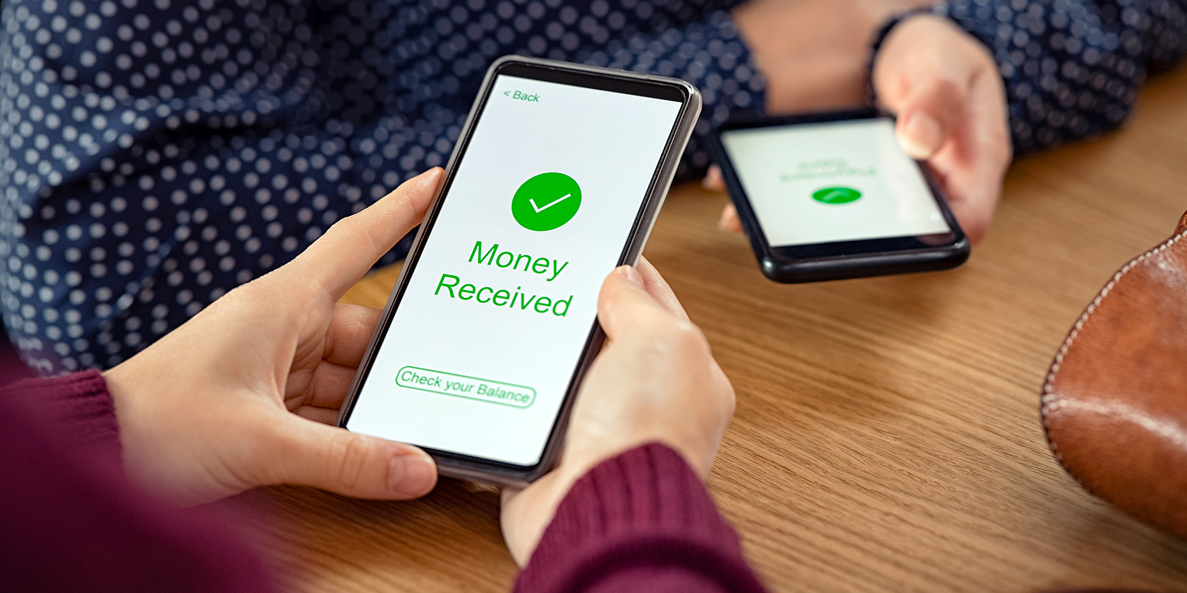 A person holding a phone displaying a "Money Received" confirmation screen | Source: Shutterstock