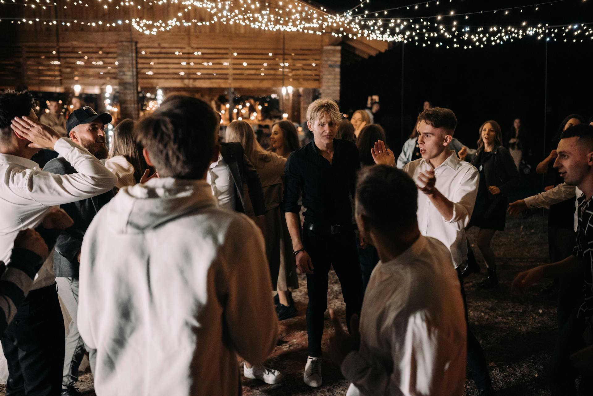 A group of people dancing at a party with string lights | Source: Pexels