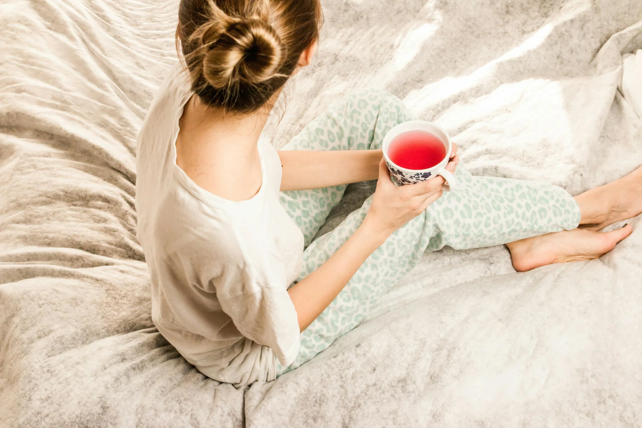 Une femme buvant du thé dans son lit ⏐ Source : Pexels