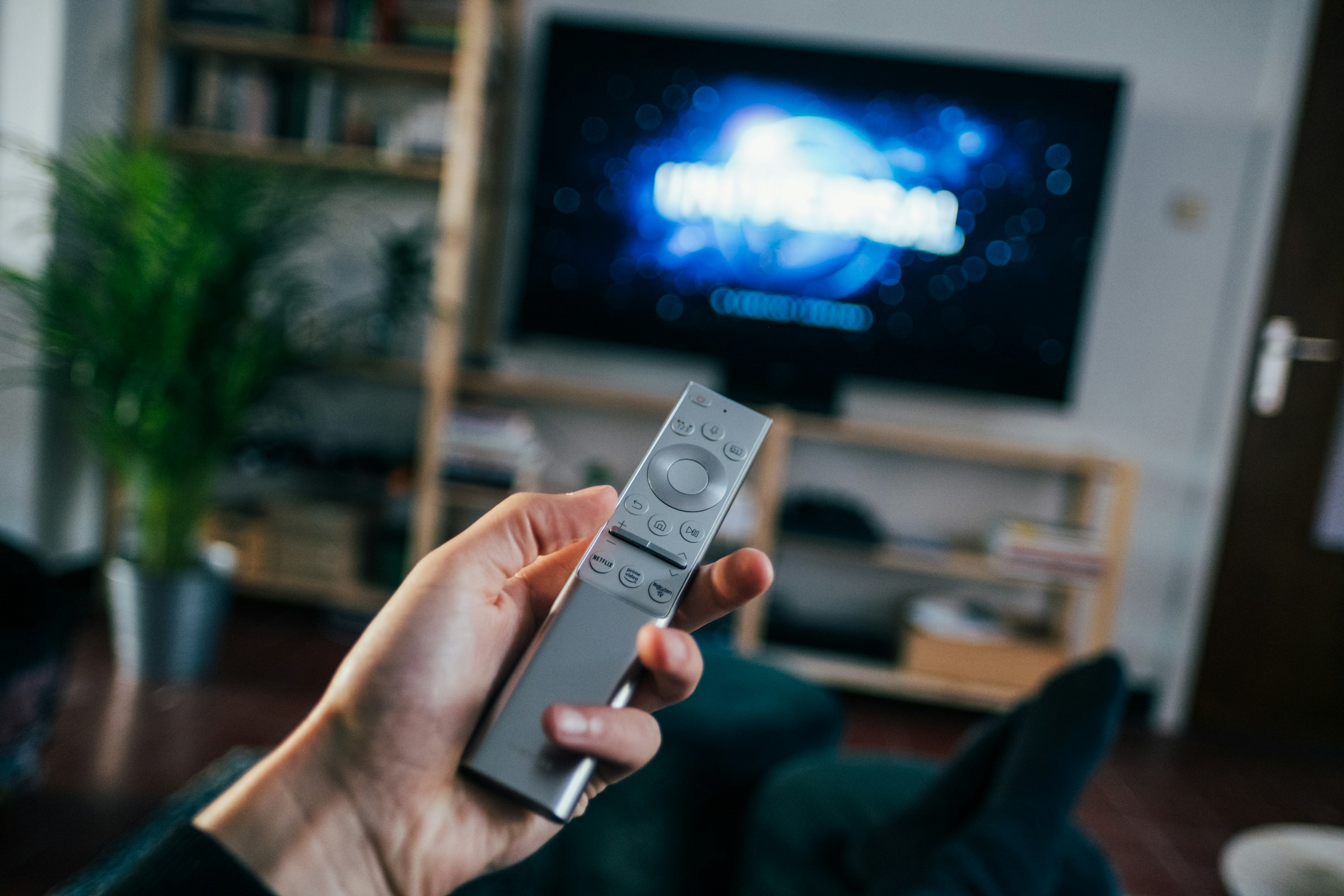 A man's hand holding a remote in a living room | Source: Unsplash