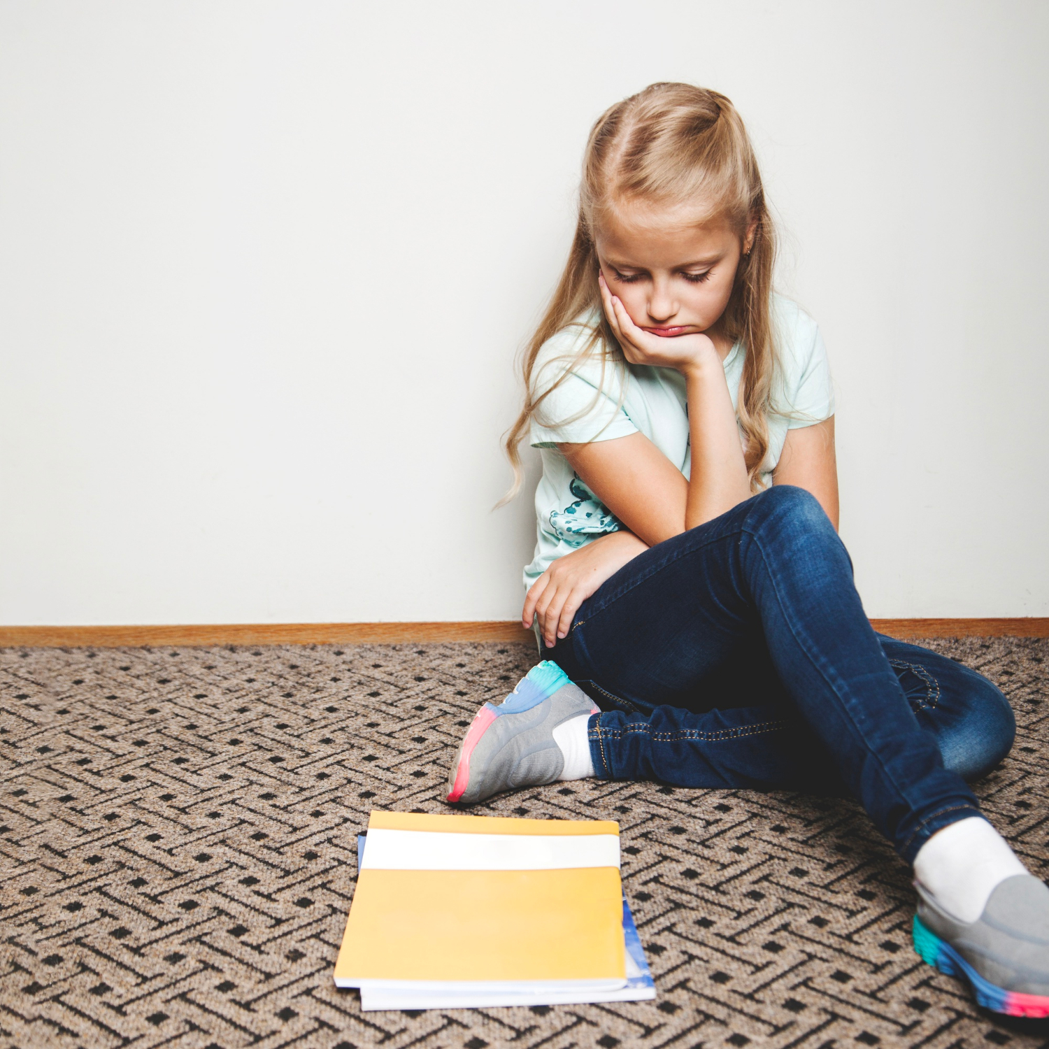 A sad young girl looking at her notebooks | Source: Freepik