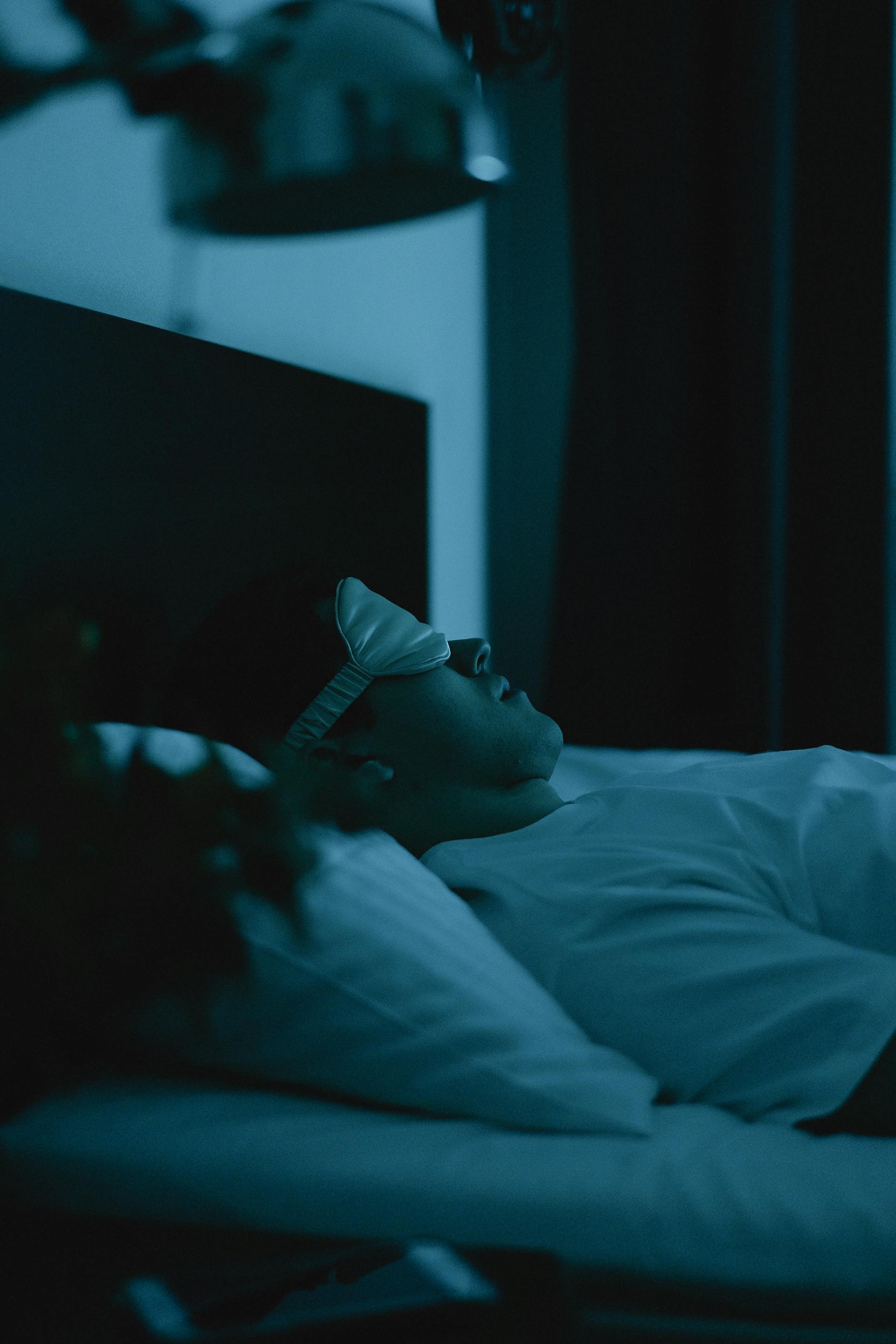 A man wearing a sleep mask while lying in bed | Source: Pexels
