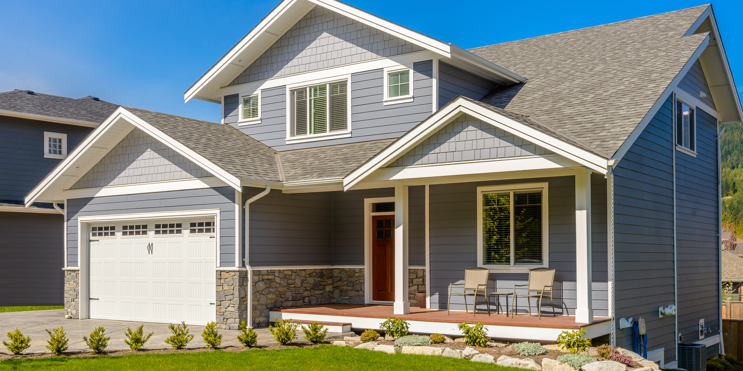 A modern two-story gray Craftsman-style home with a covered front porch and well-kept landscaping | Source: Shutterstock