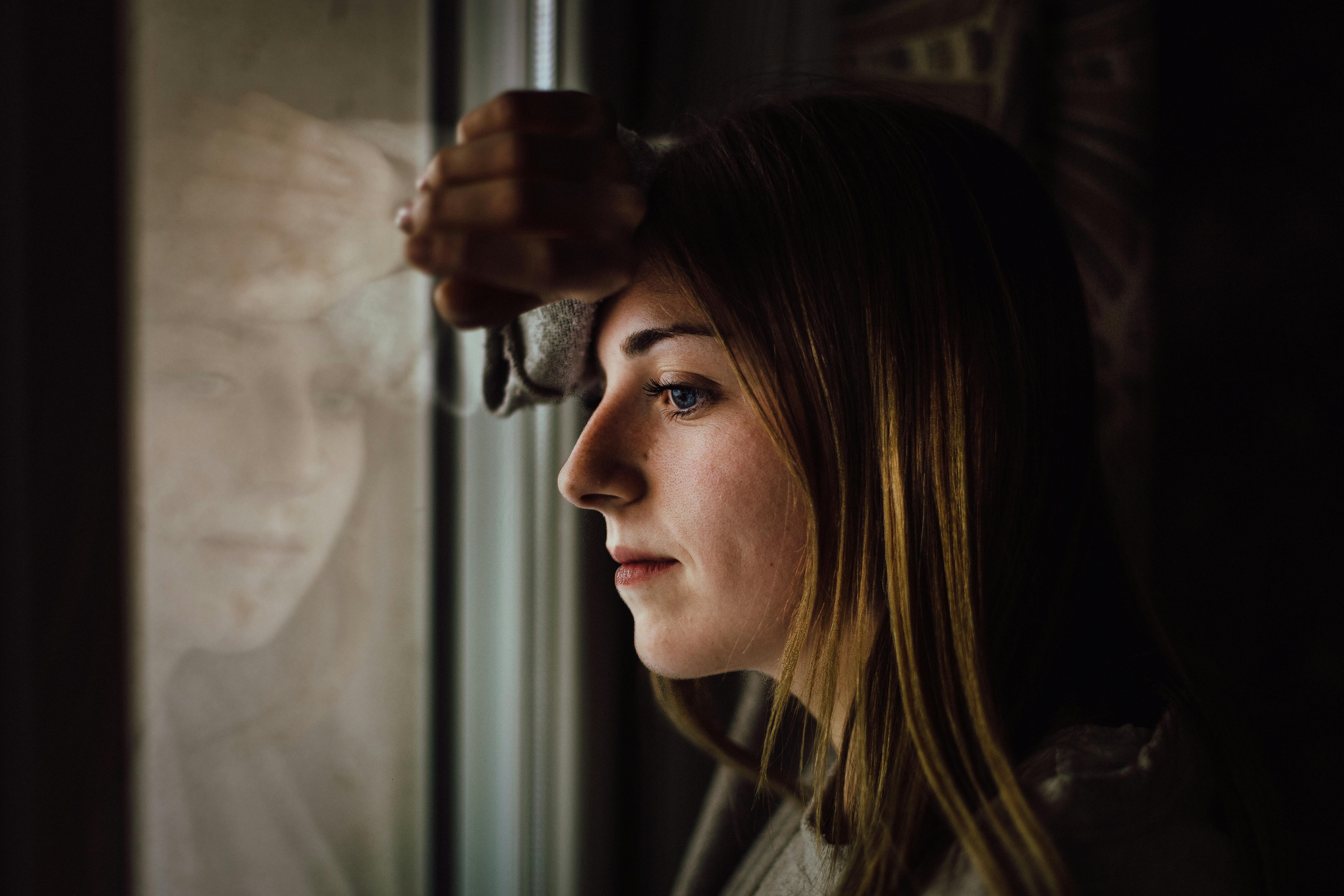 Sad woman looks out of the window | Source: Pexels