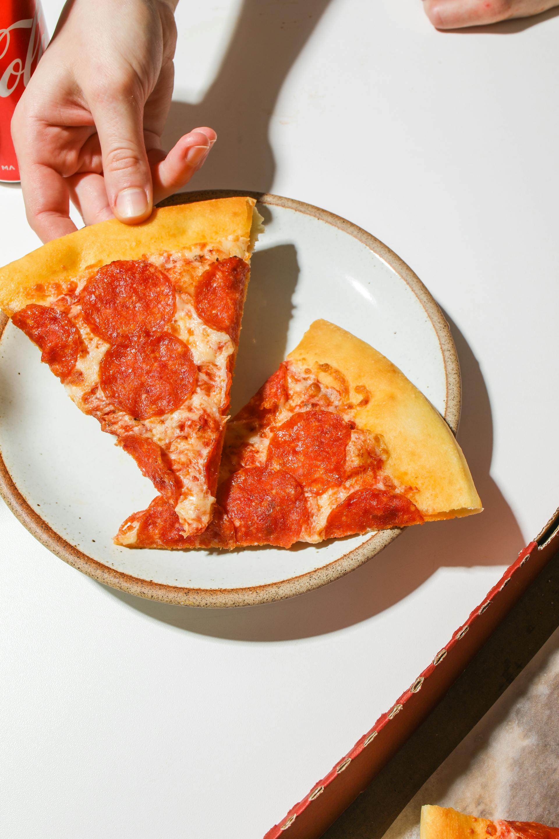 Someone taking a slice of pizza from a plate | Source: Pexels