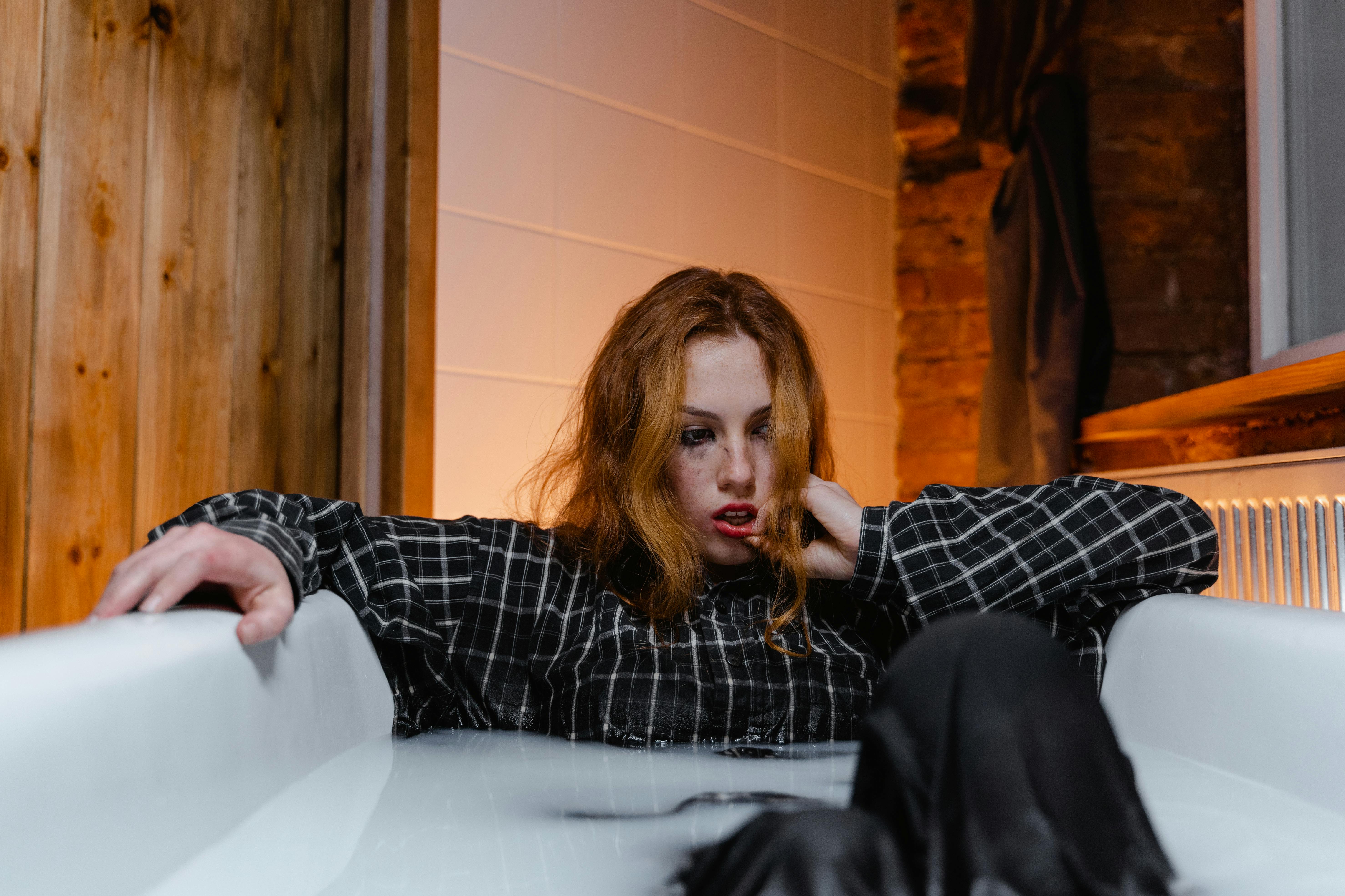 A heartbroken woman crying while sitting fully-clothed in a bathtub | Source: Pexels