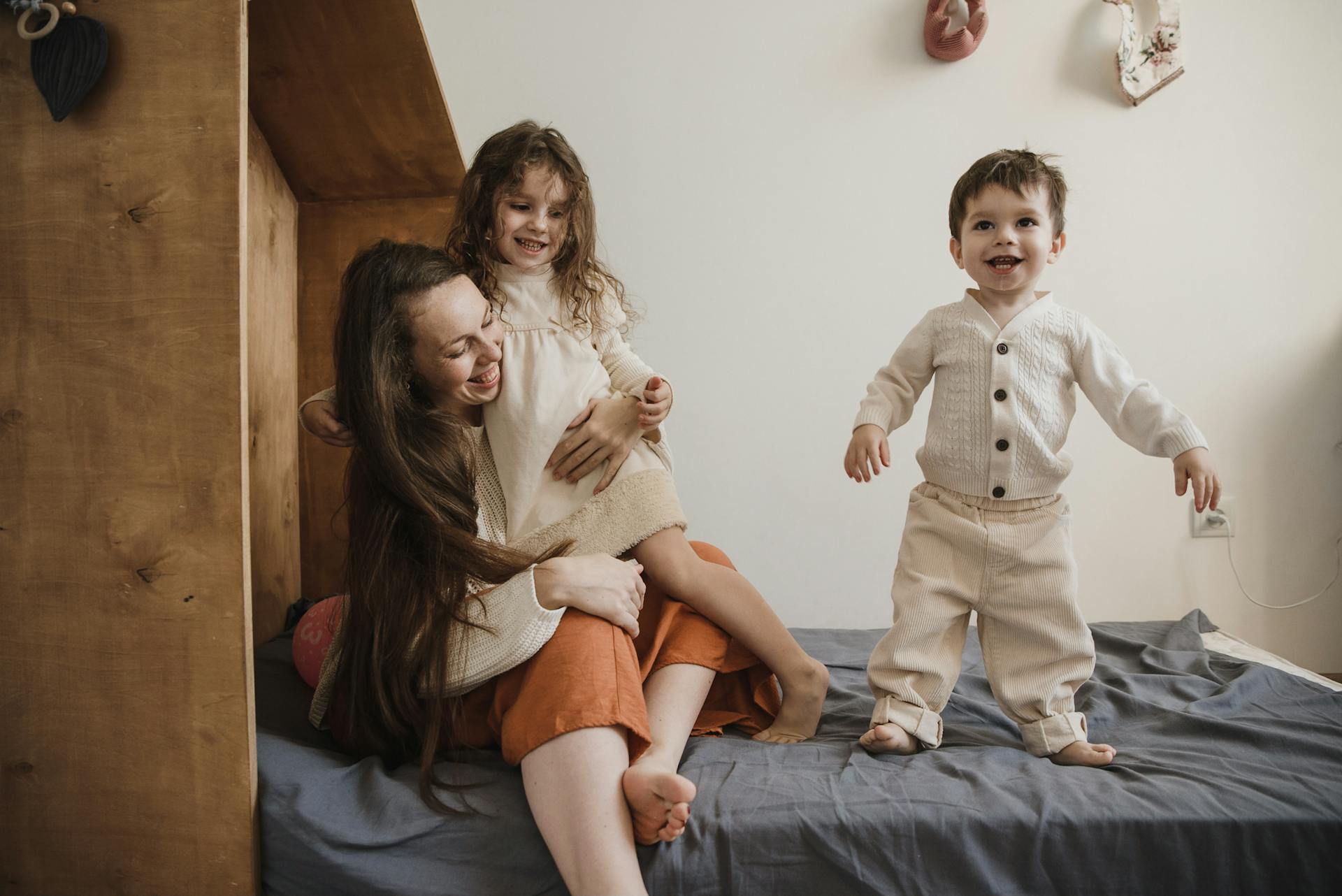 A woman playing with her children on the bed | Source: Pexels