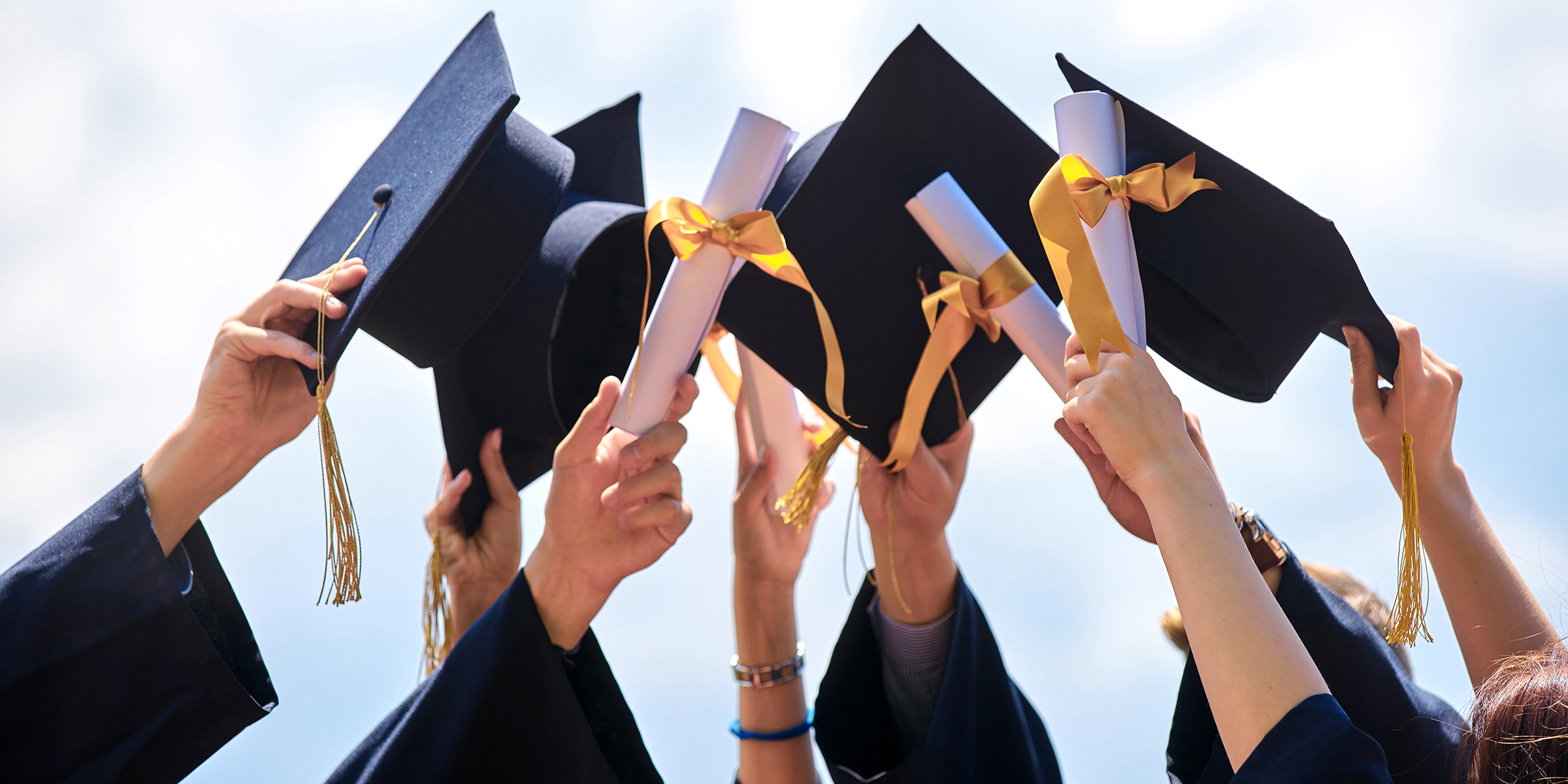 Students holding their graduation caps | Source: Shutterstock
