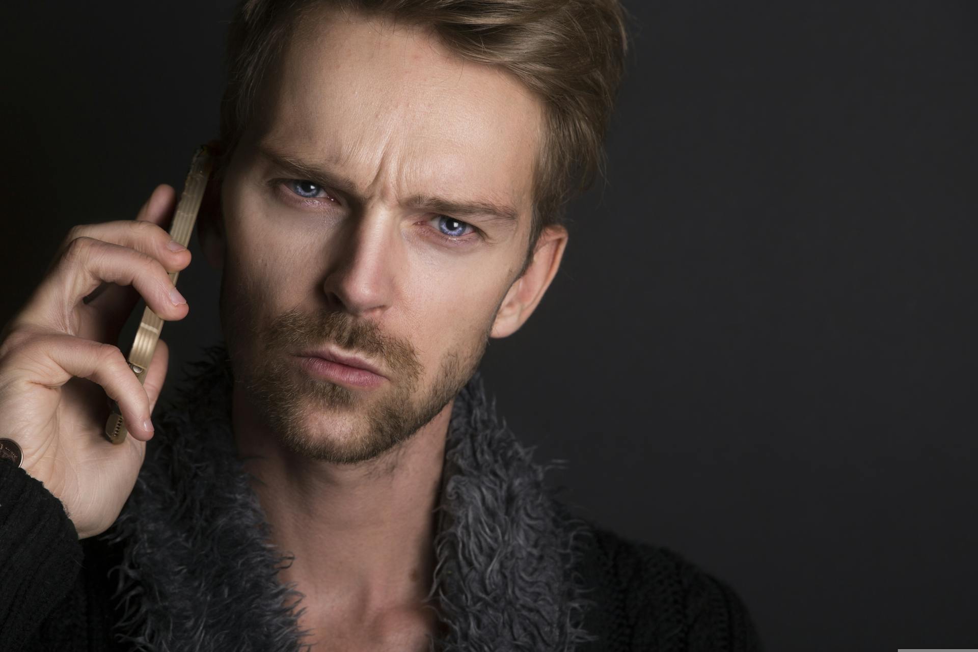 A man with blue eyes and a furrowed brow talking on a phone | Source: Pexels