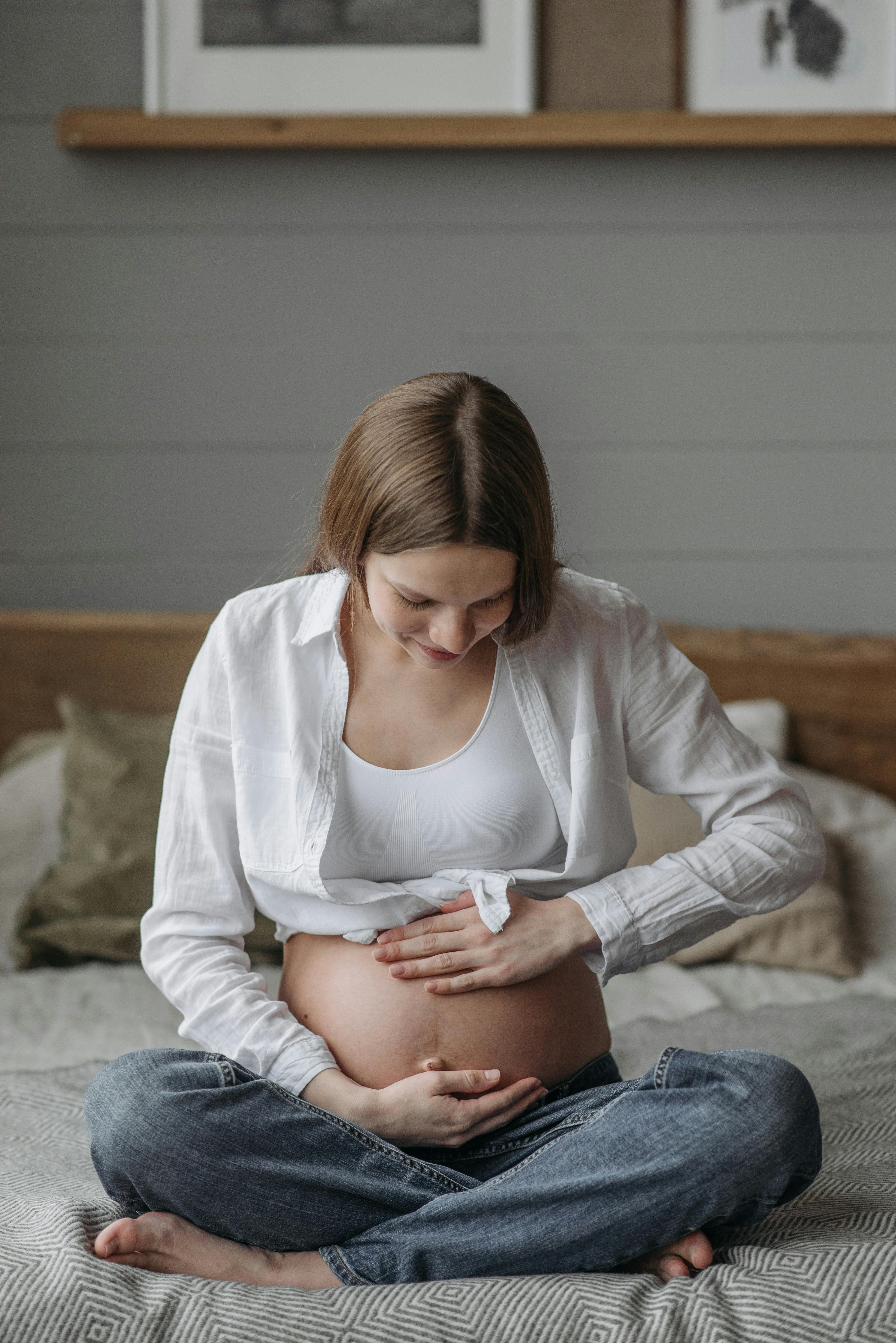A pregnant woman cradling her baby bump | Source: Pexels