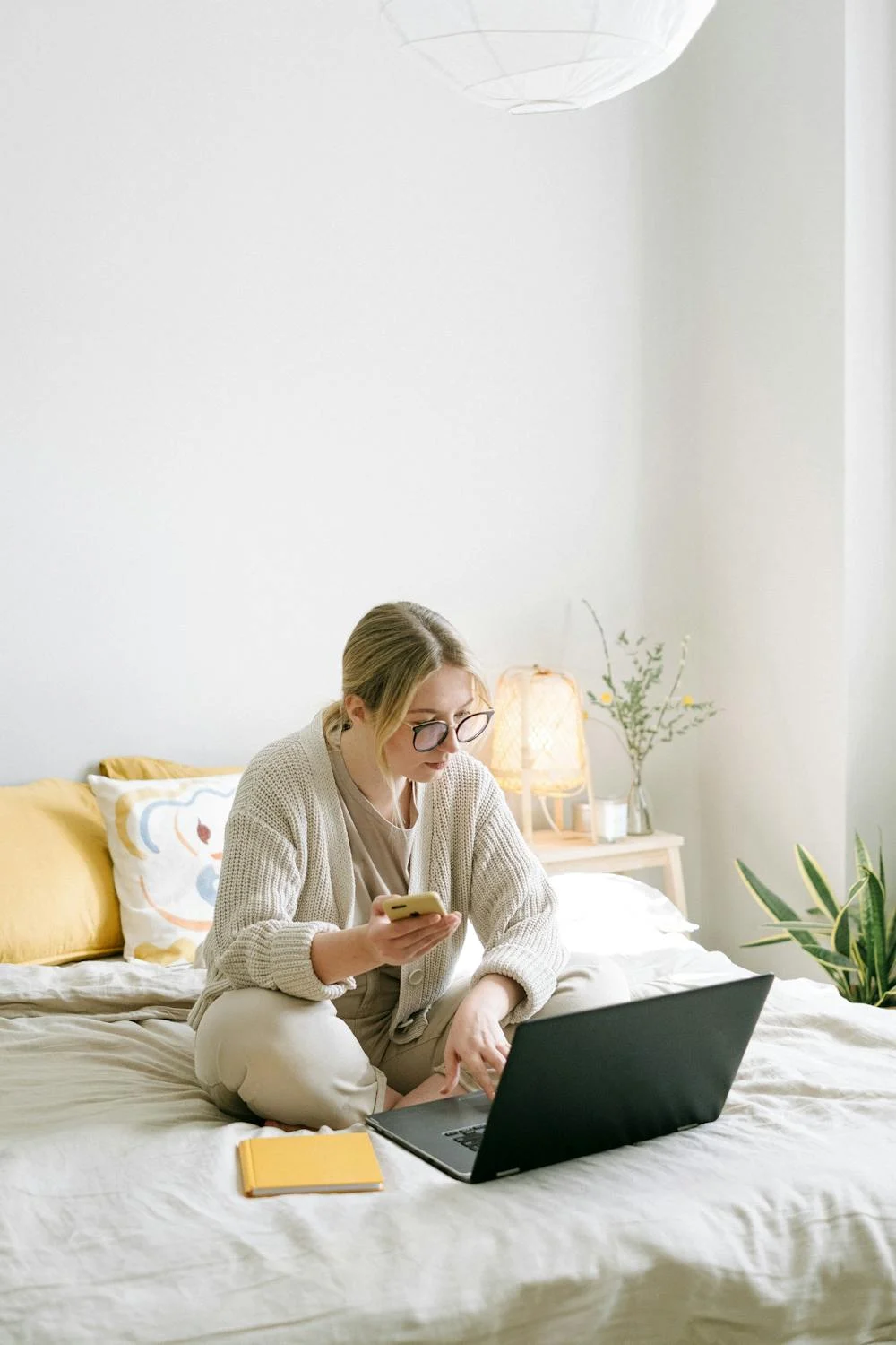 A woman with her phone looking at her laptop | Source: Pexels