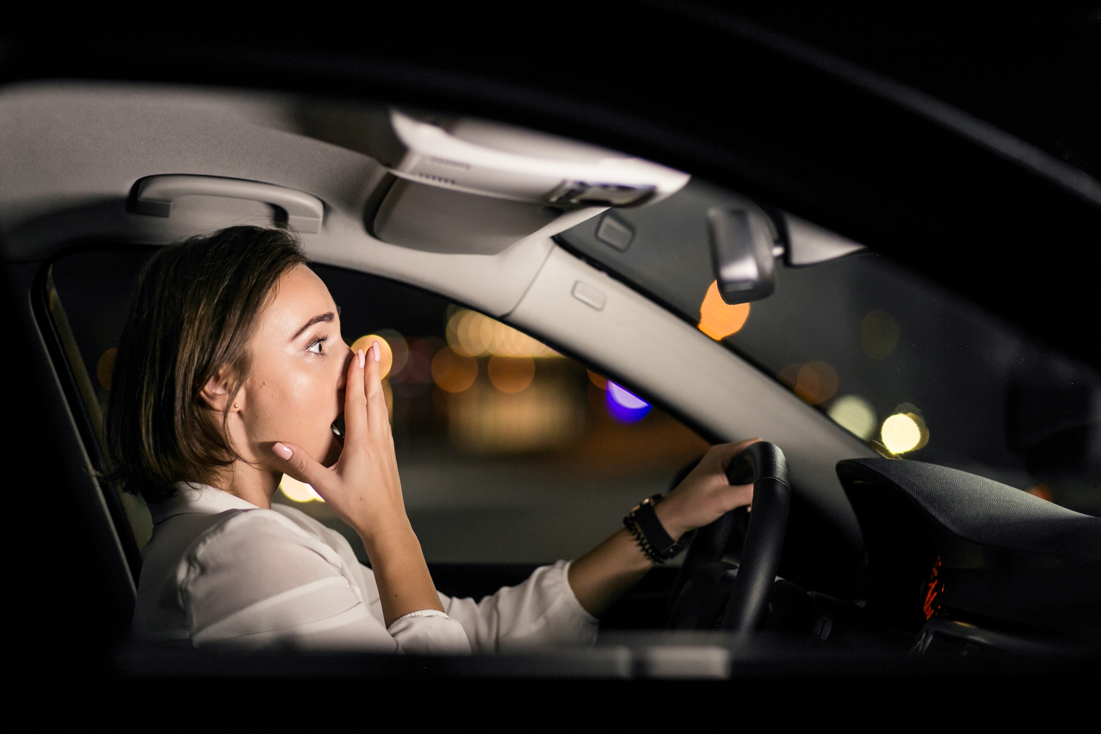 Photo de nuit d'une femme choquée conduisant une voiture | Source : Freepik