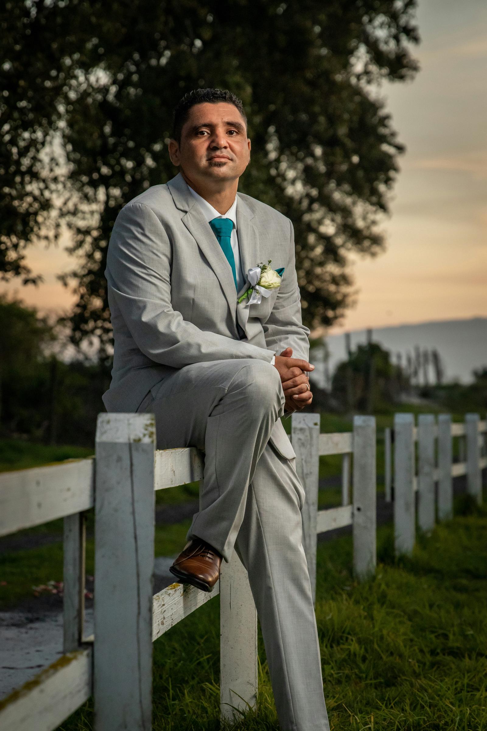 Man in a suit sitting on a wooden fence | Source: Unsplash