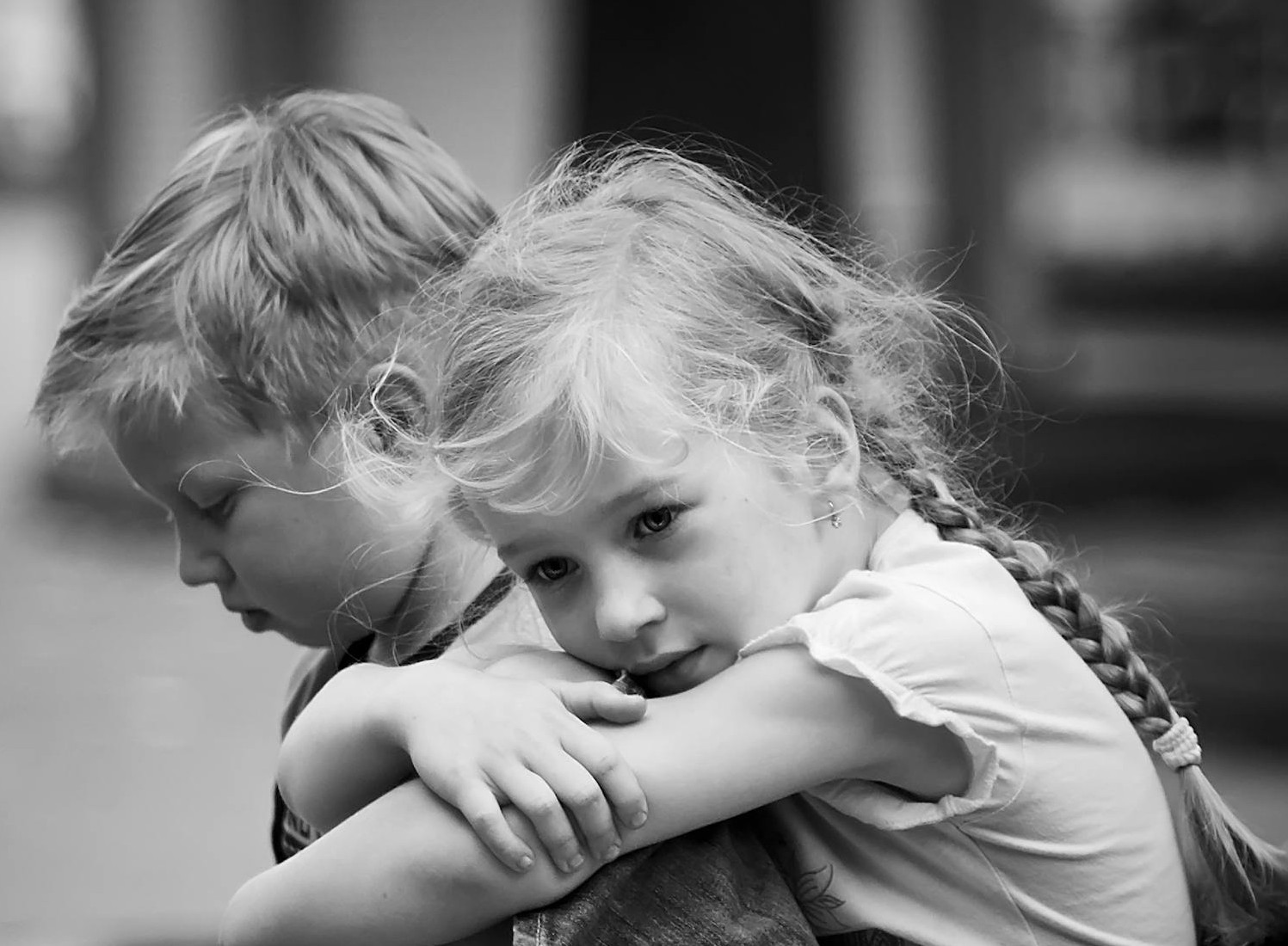 Photographie en niveaux de gris d'un petit garçon et d'une petite fille tristes assis ensemble | Source : Pexels