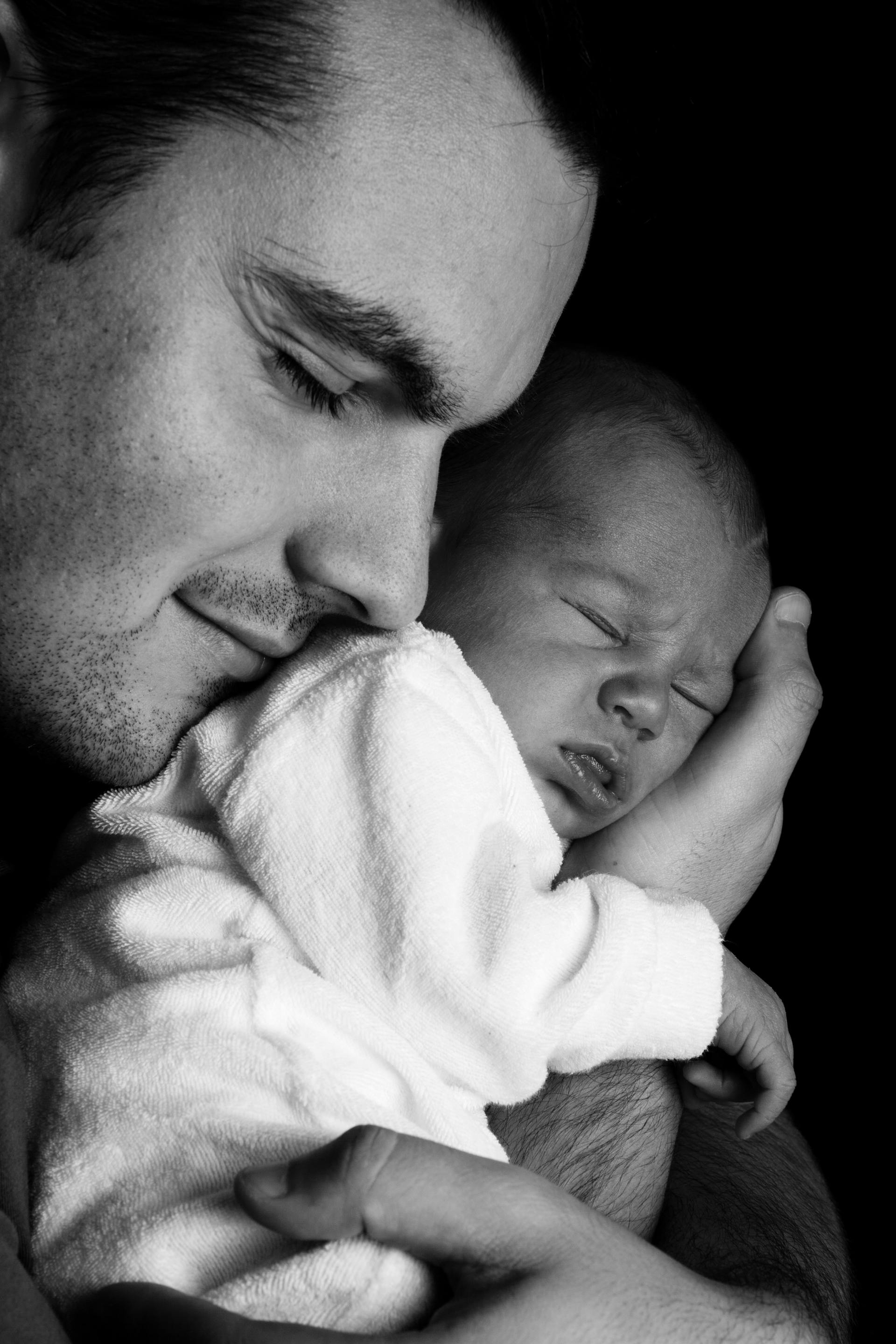 Grayscale photo of a man carrying a newborn baby | Source: Pexels