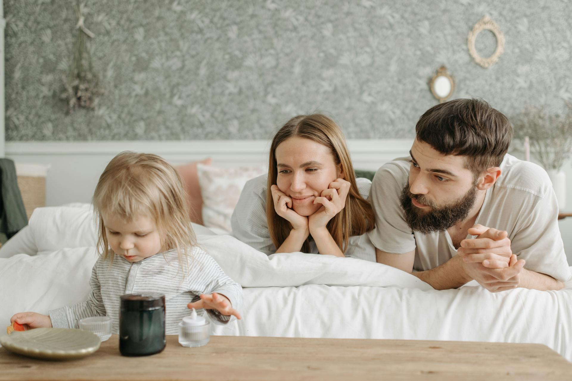 A couple lying on the bed and looking at their child | Source: Pexels
