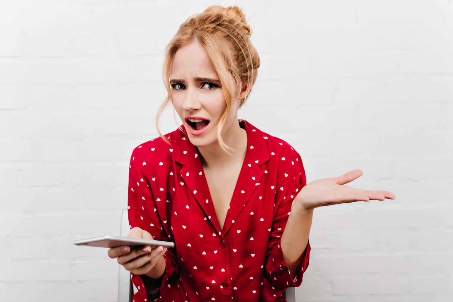 A confused woman holding her phone | Source: Freepik
