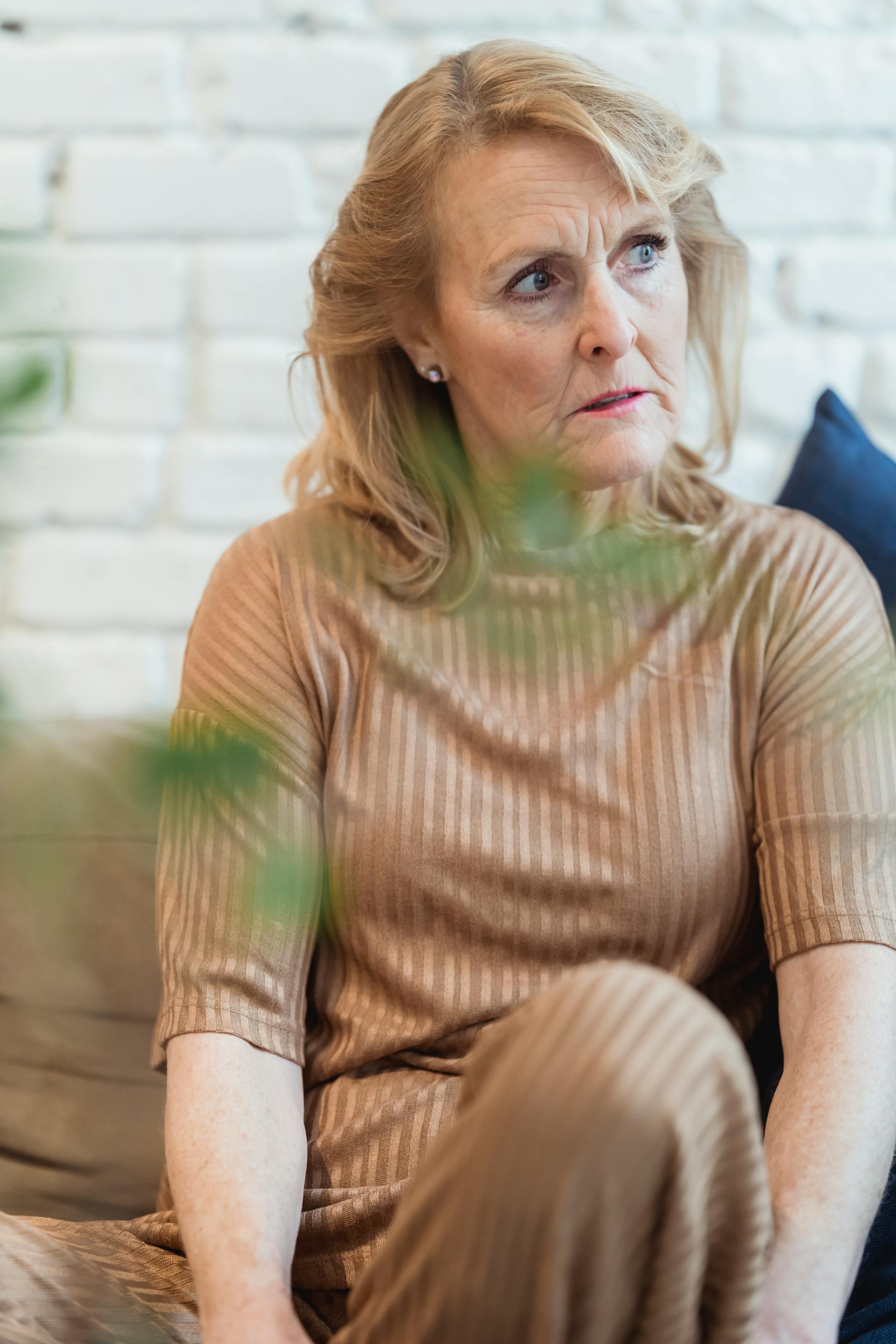 A pensive middle-aged woman sitting on the couch | Source: Pexels