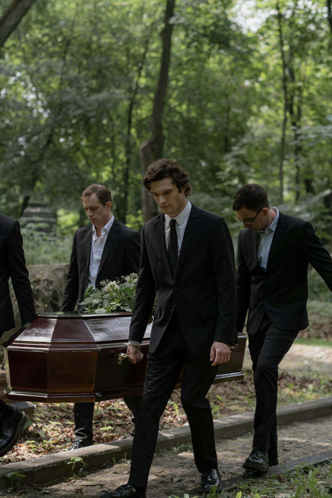 Somberly dressed men carrying a casket | Source: Pexels