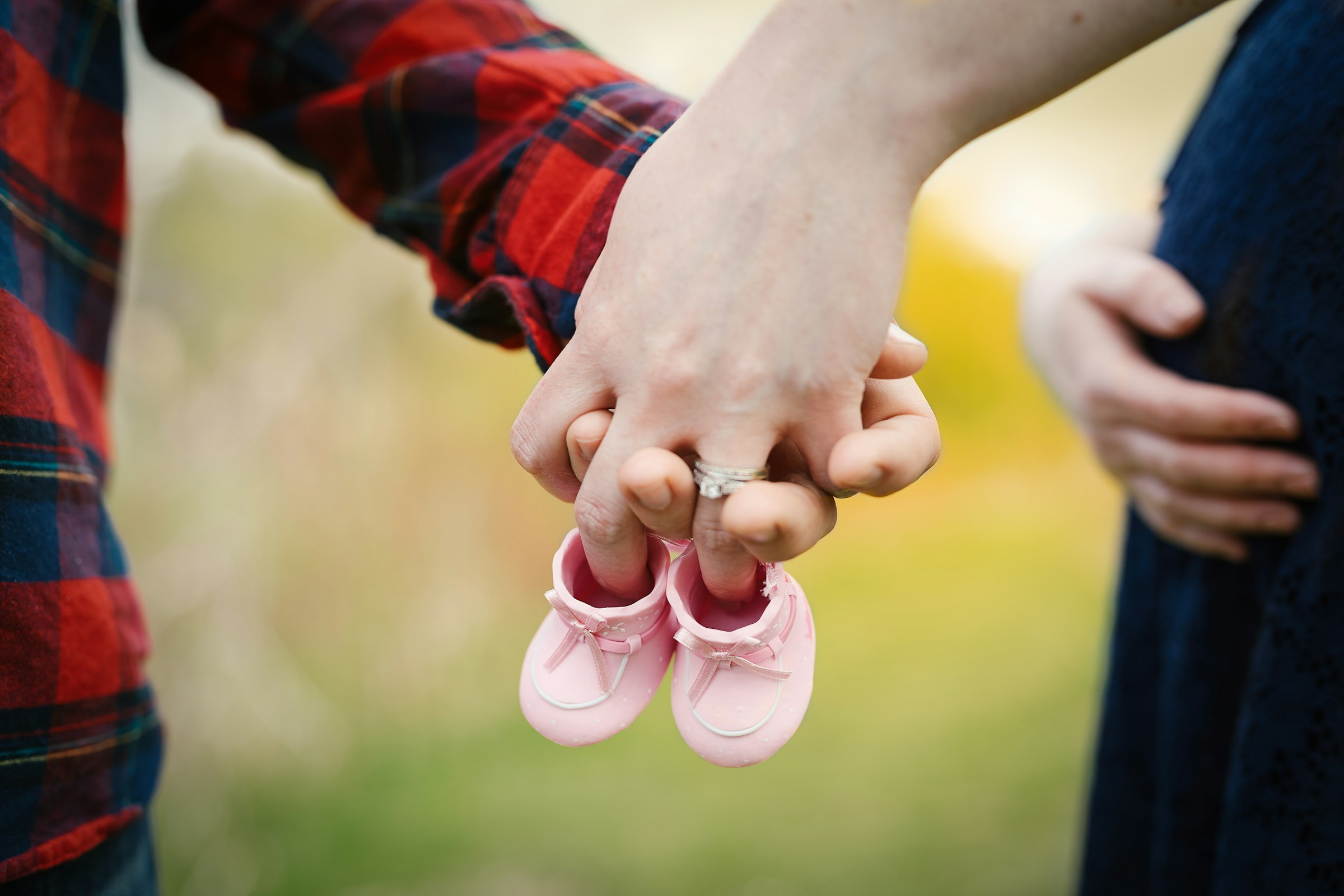 An expecting couple holding a pair of tiny pink shoes | Source: Unsplash