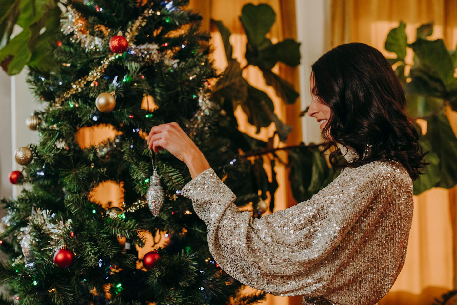 Uma mulher alegre decorando uma árvore de Natal | Fonte: Pexels