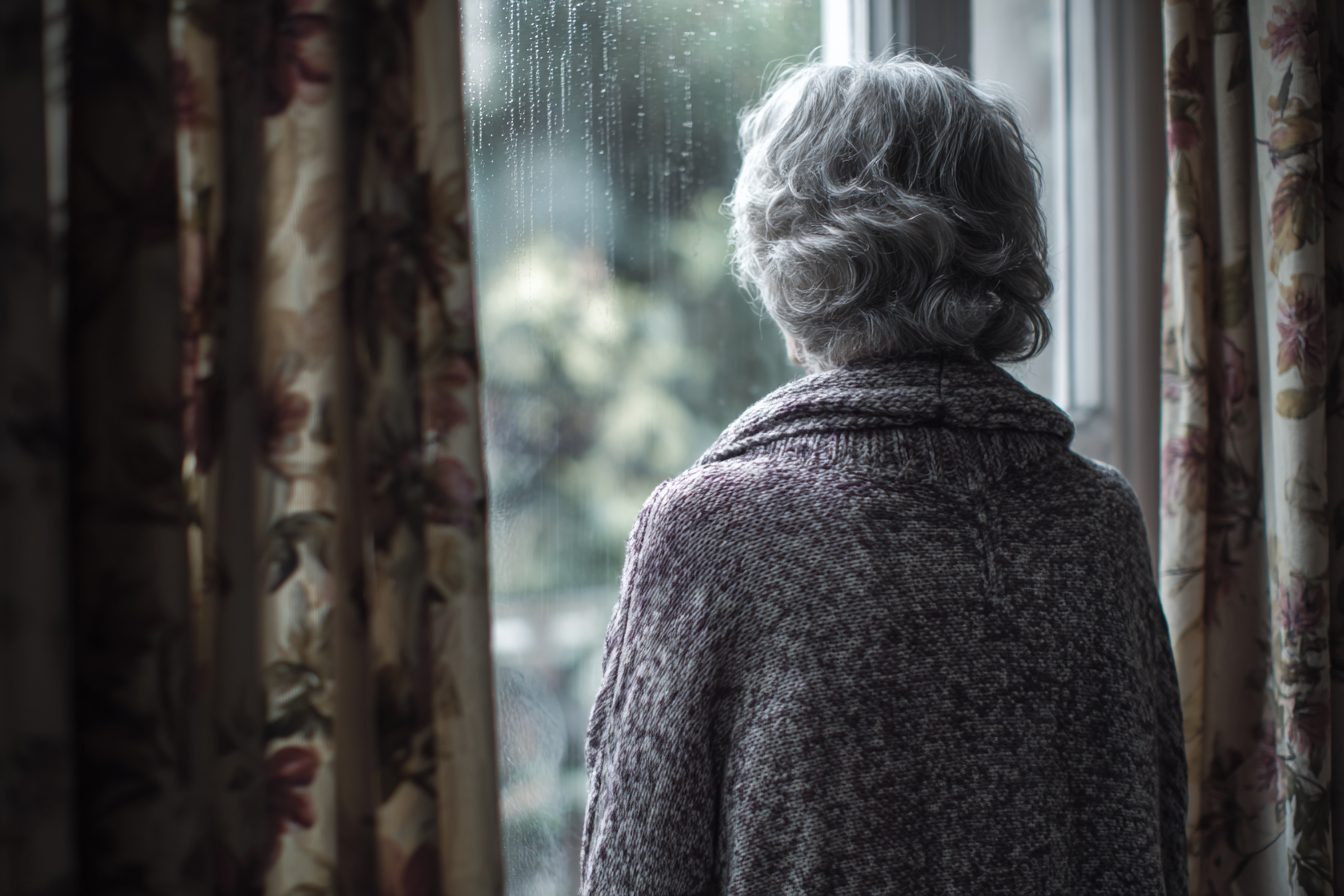 An older woman standing near a window | Source: Midjourney