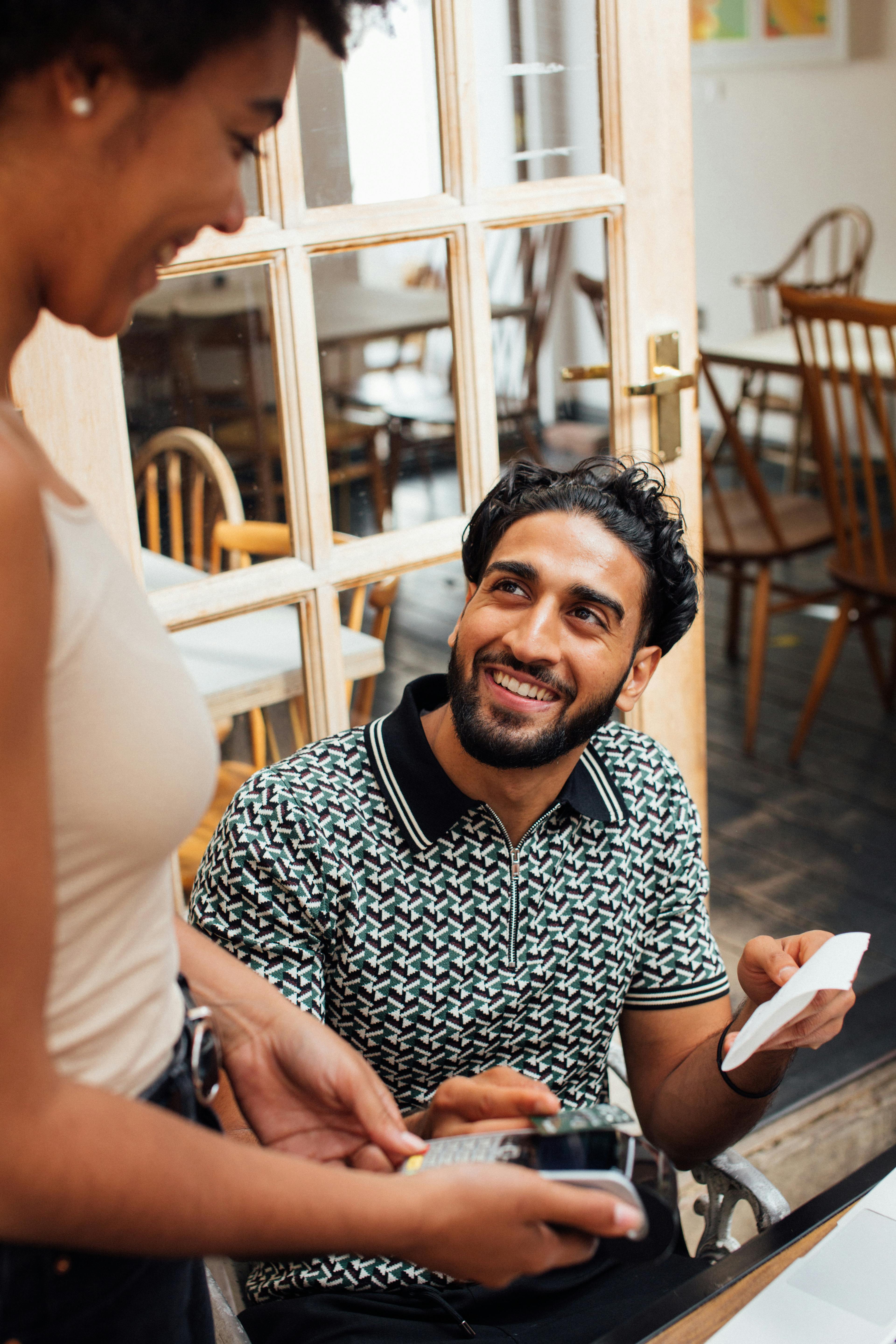 Man smiling while talking to a waitress | Source: Pexels
