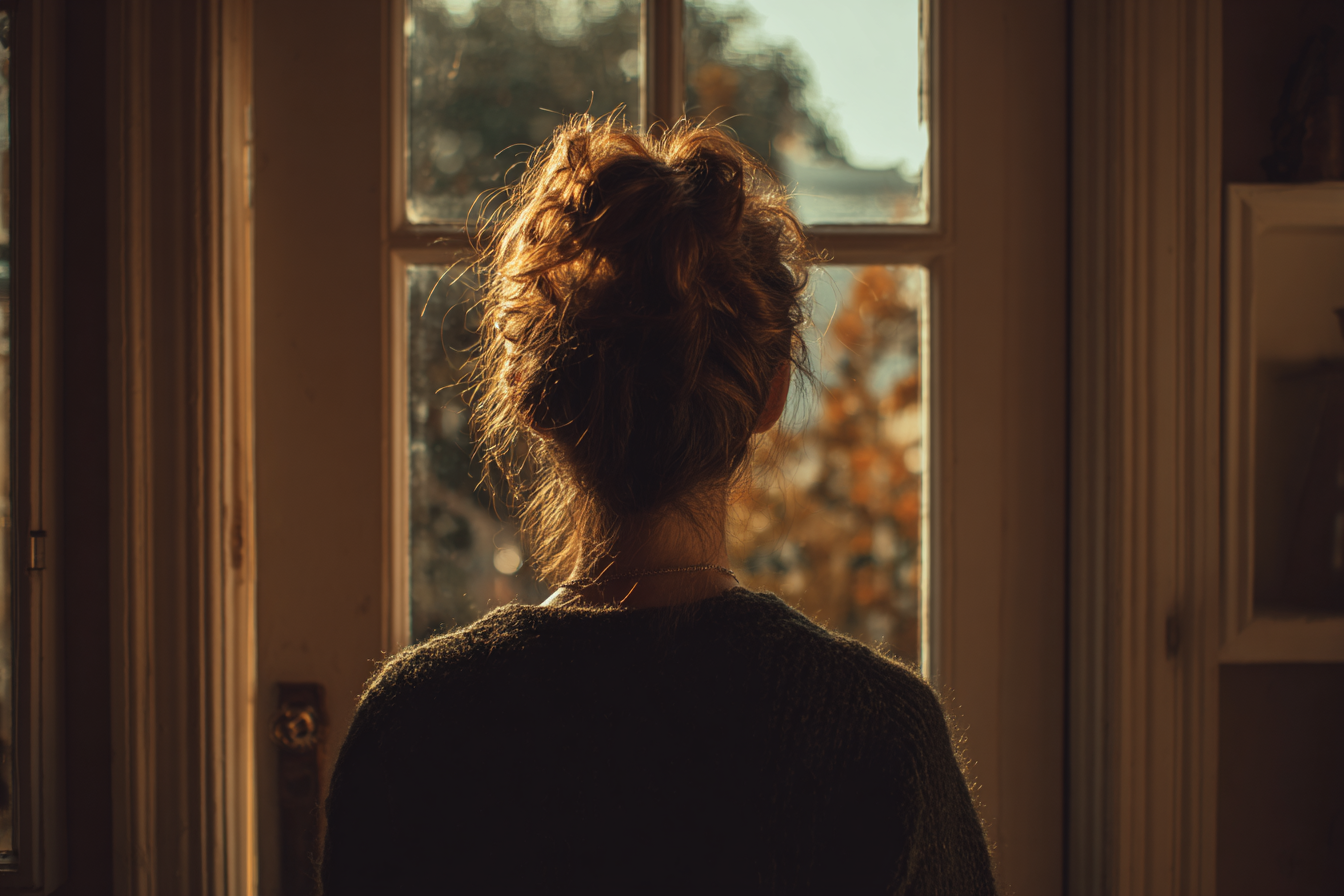 A woman looking outside a window | Source: Midjourney