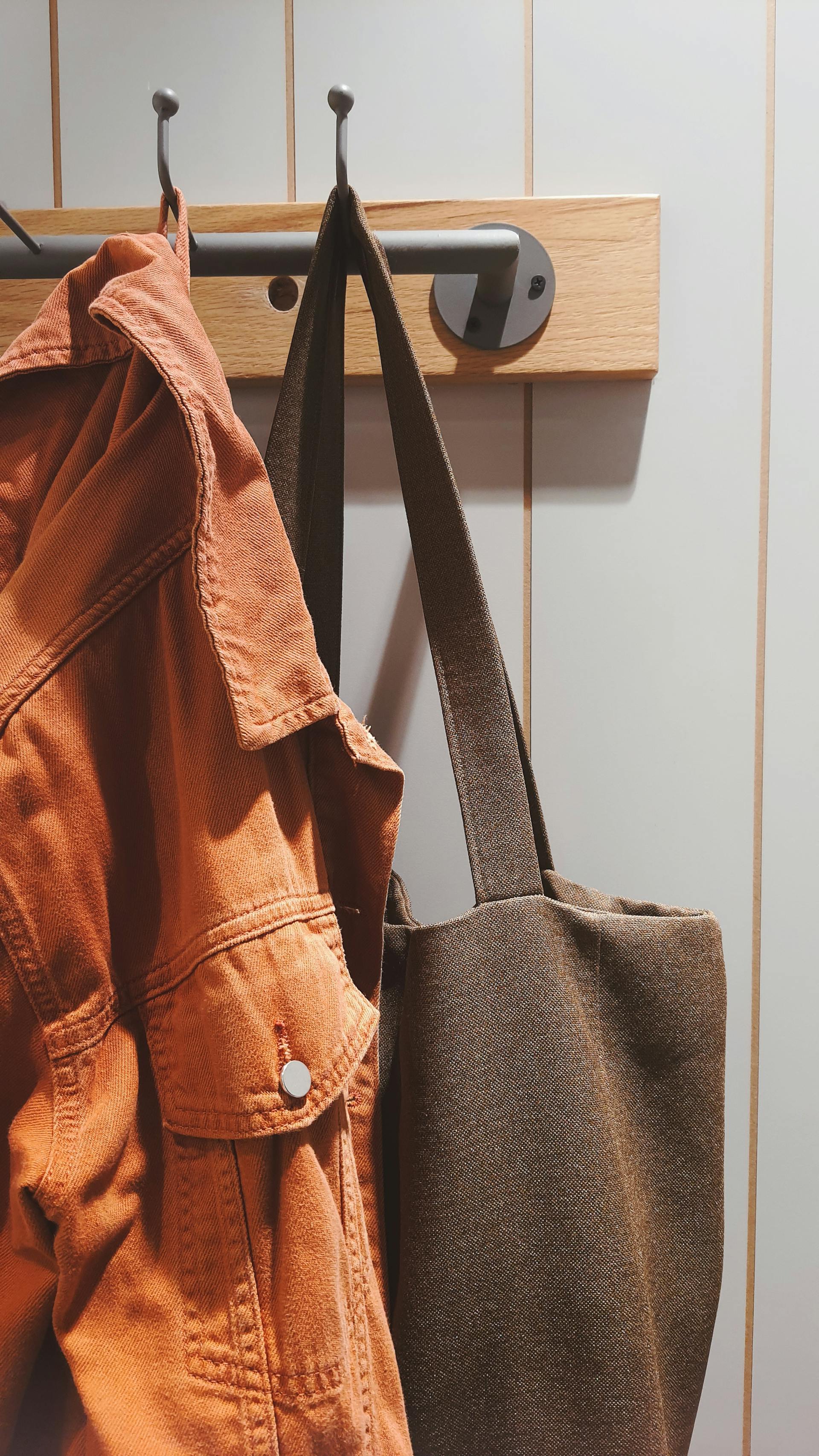 A coat and bag hanging on a rack | Source: Pexels