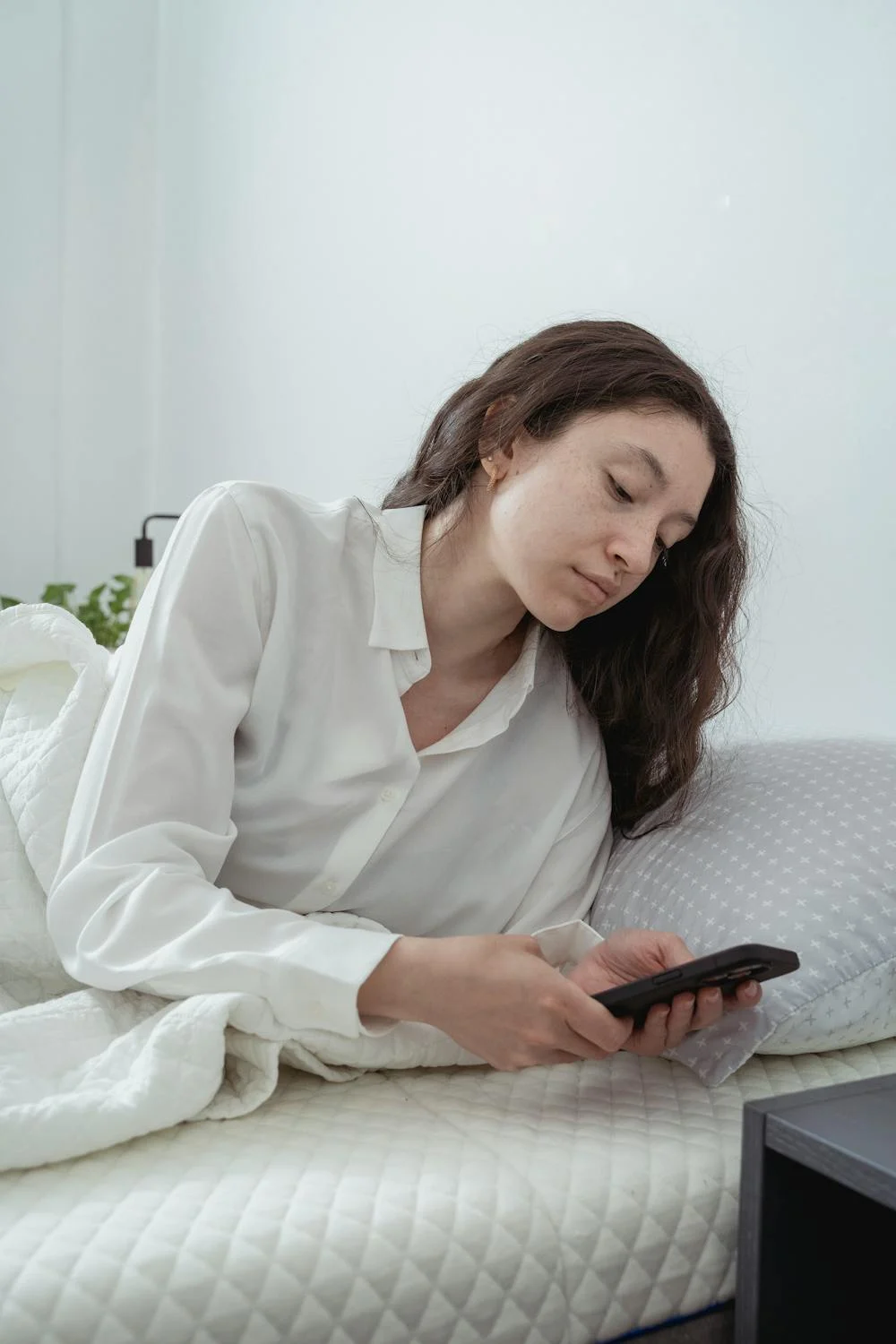 A woman in bed looking at her phone | Source: Pexels