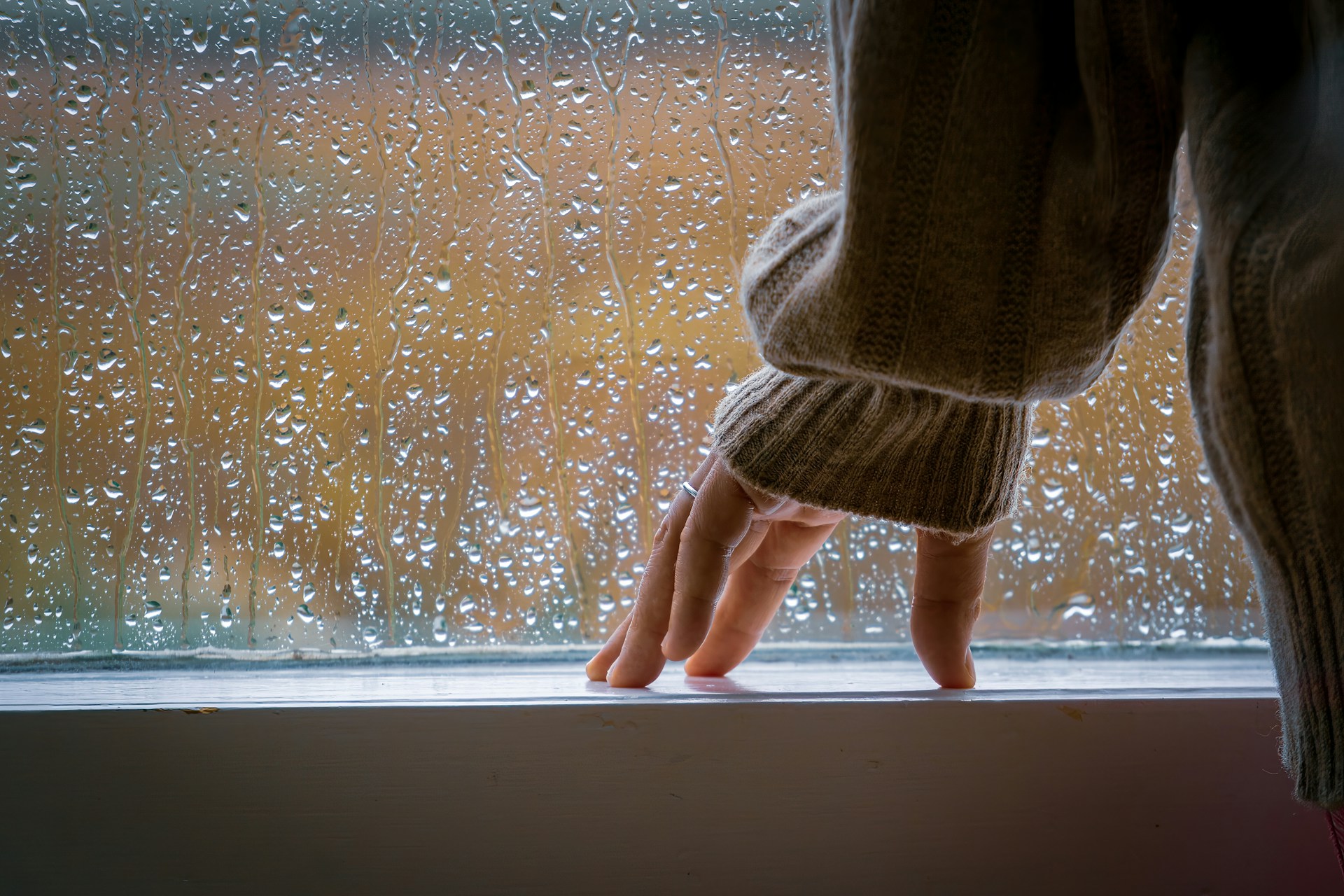 A woman standing near a window and watching the rain | Source: Unsplash
