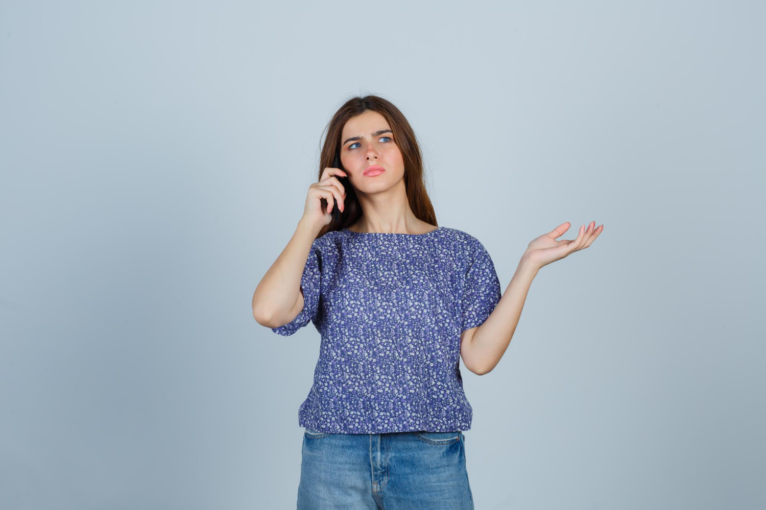 A frustrated young lady talking on the phone | Source: Freepik